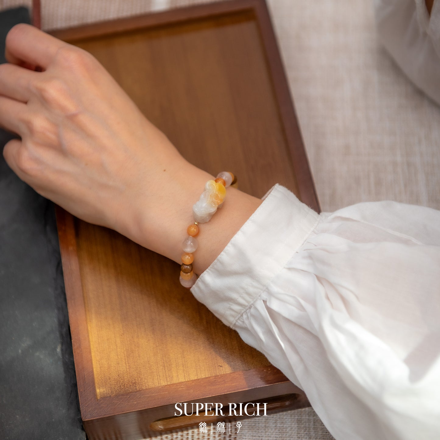 Hand wearing a beaded bracelet with a wooden surface in the background