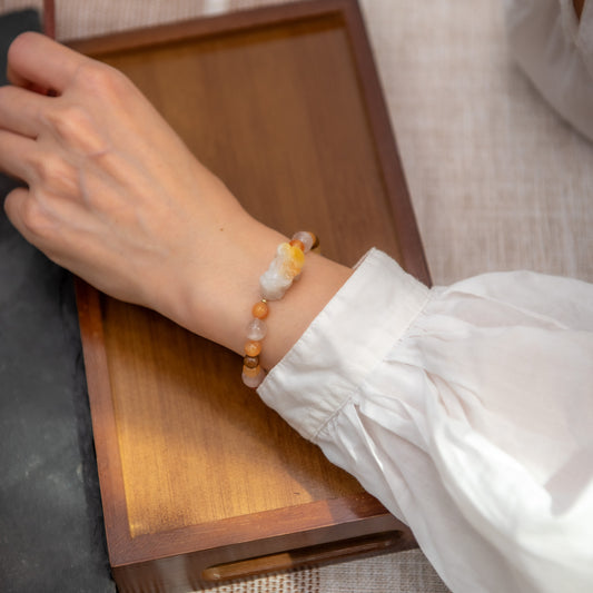 Person wearing a beaded bracelet on a wooden surface