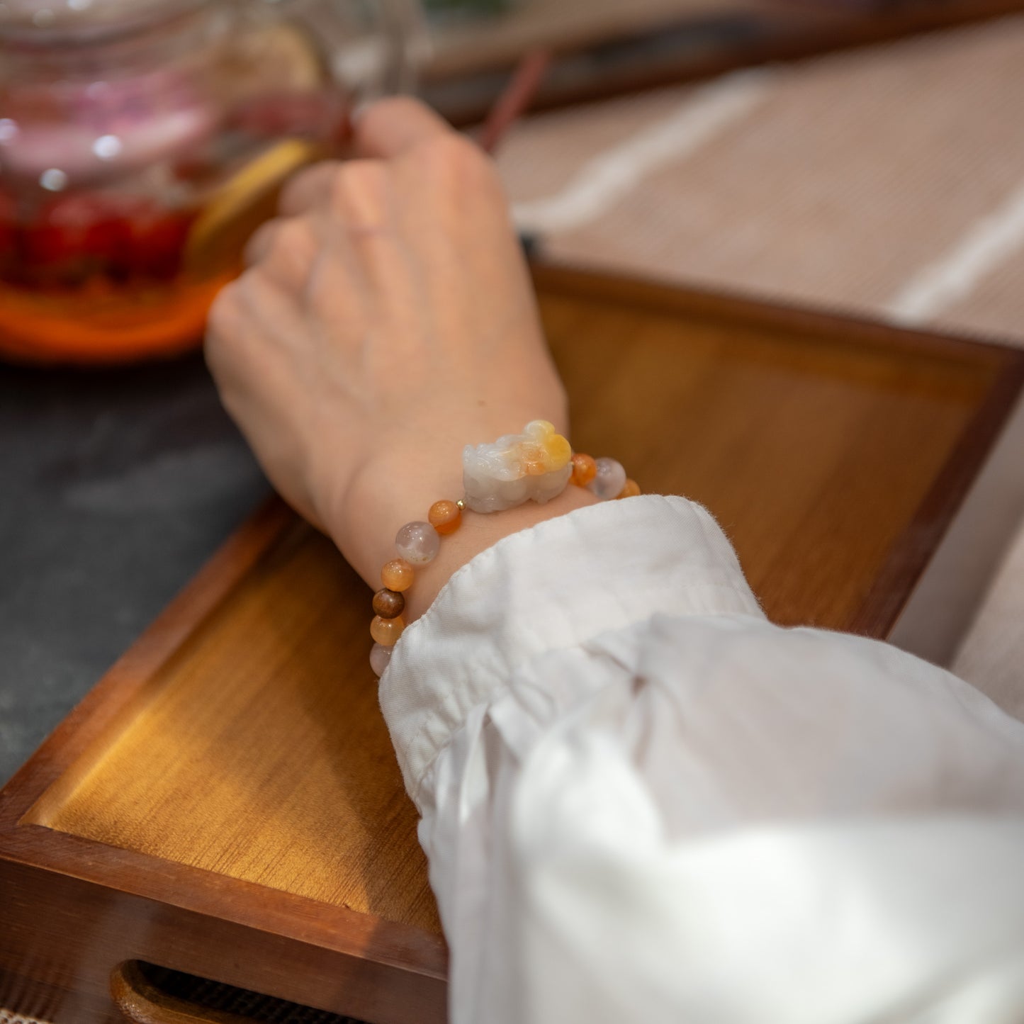 Person wearing a bracelet with a wooden surface and blurred background