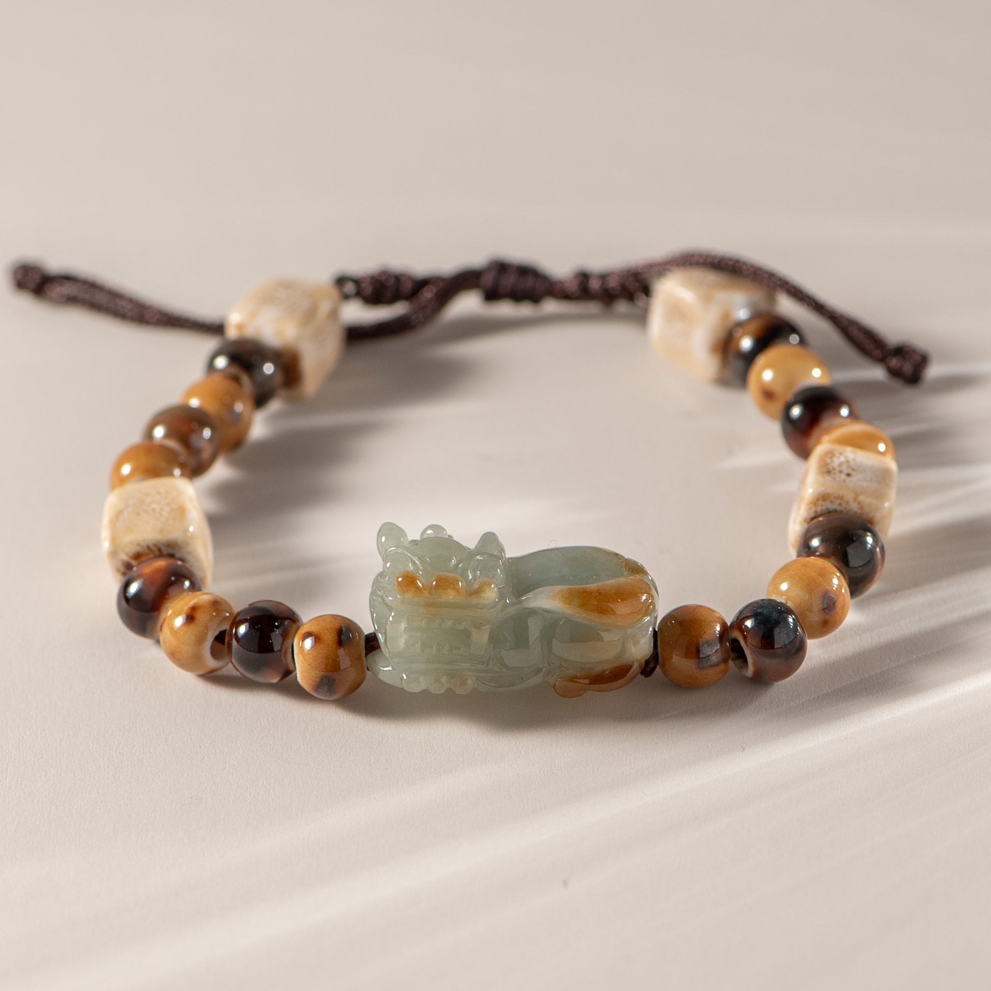 Bracelet with beads and a jade charm on a neutral background