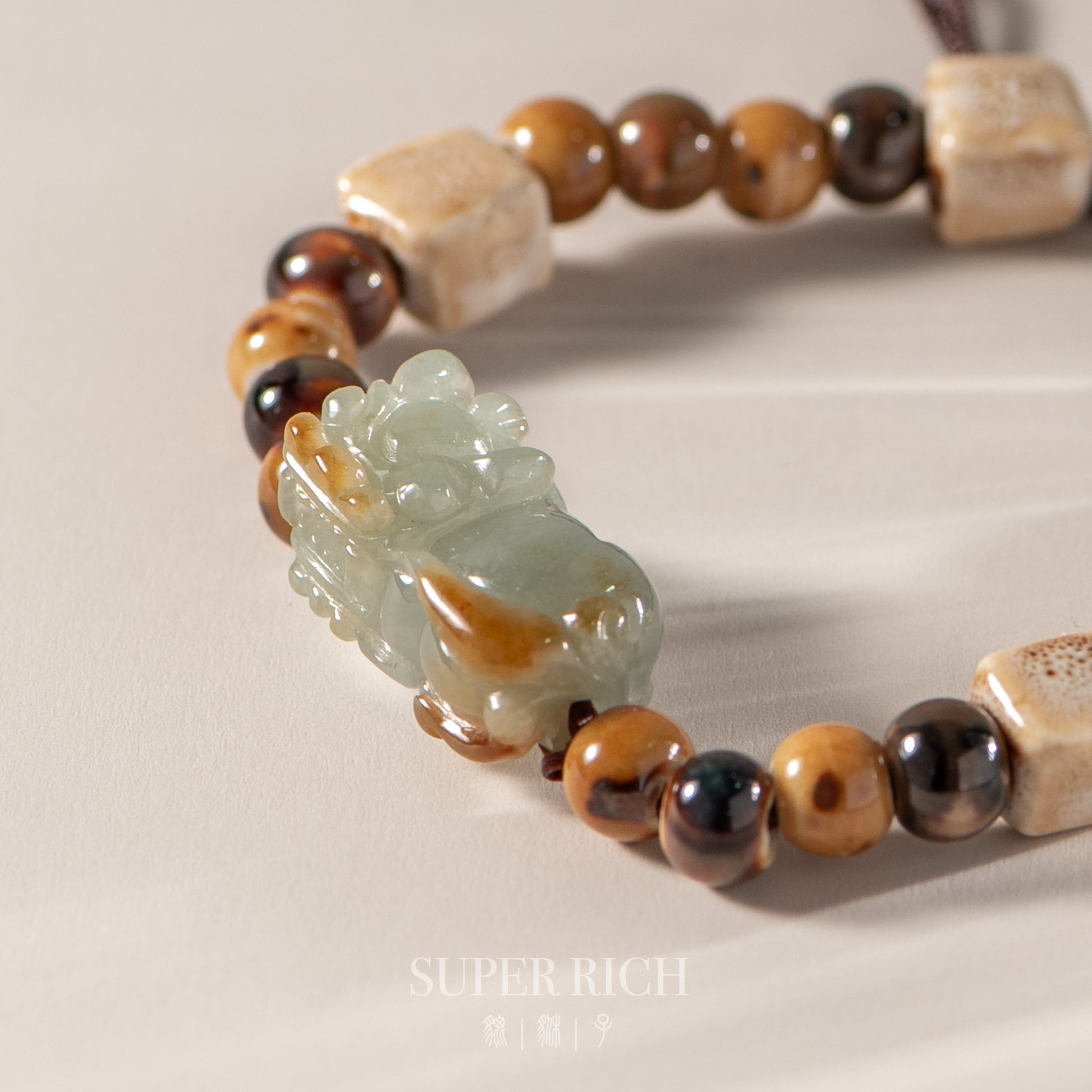 Beaded bracelet with a jade charm on a neutral background, featuring the brand 'Super Rich'.