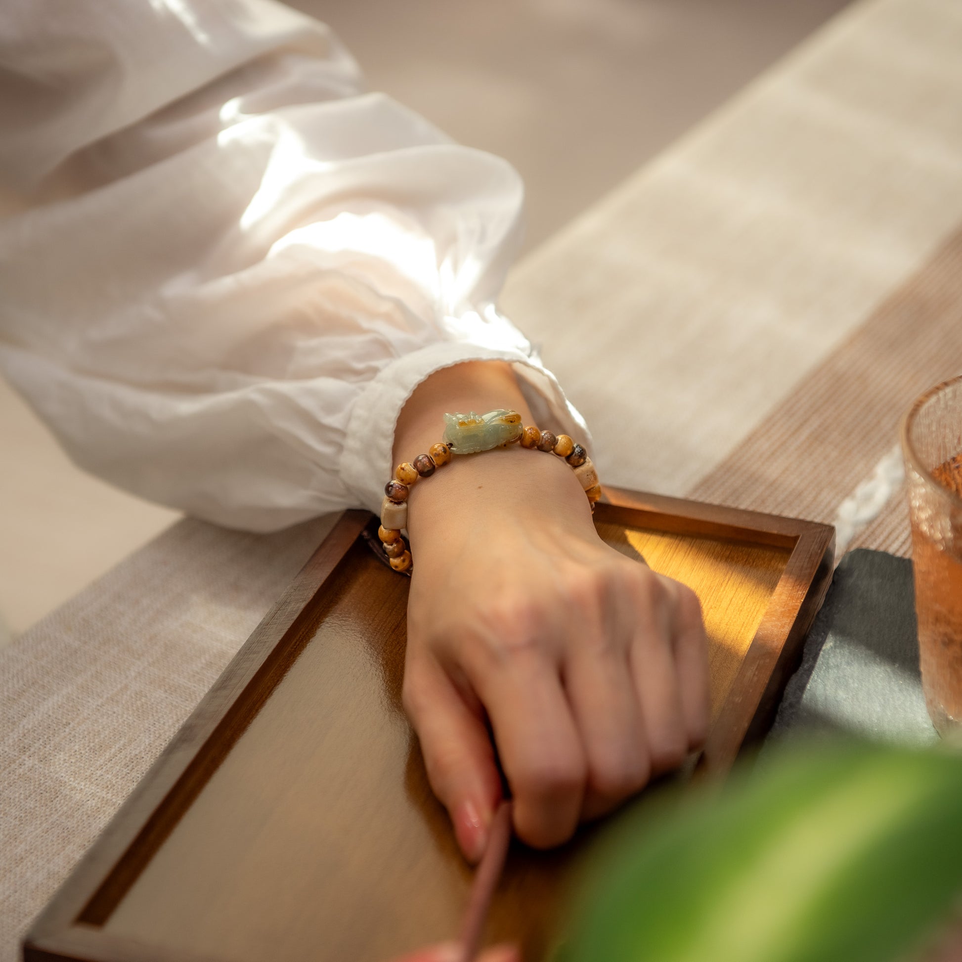Hand wearing a beaded bracelet on a wooden surface with a blurred background