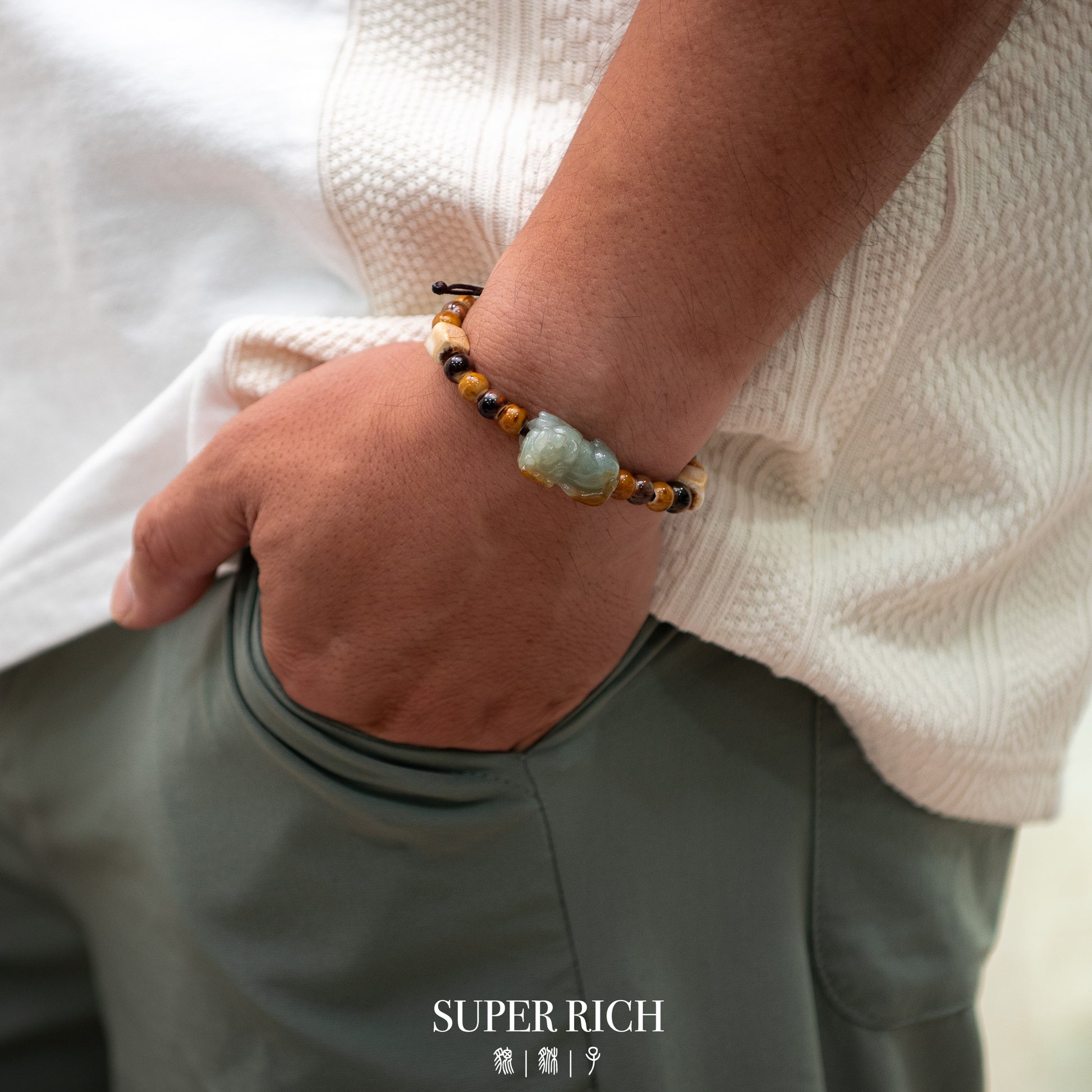 Person wearing a bracelet with a visible brand logo, holding a white shirt.