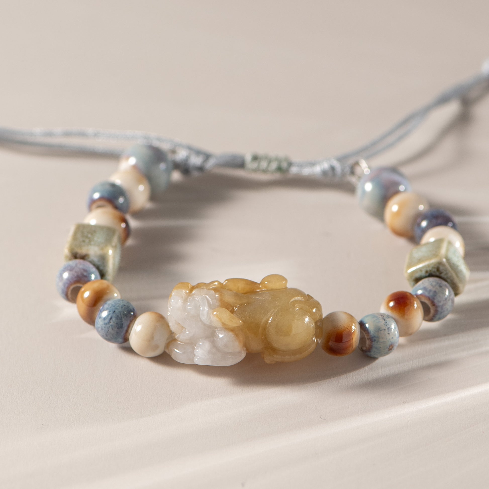 Beaded bracelet with a large central stone on a neutral background