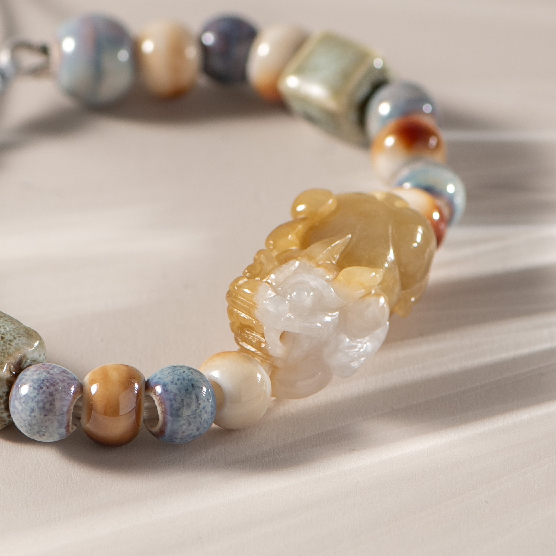 Jewelry with multicolored beads and a central carved stone on a neutral background