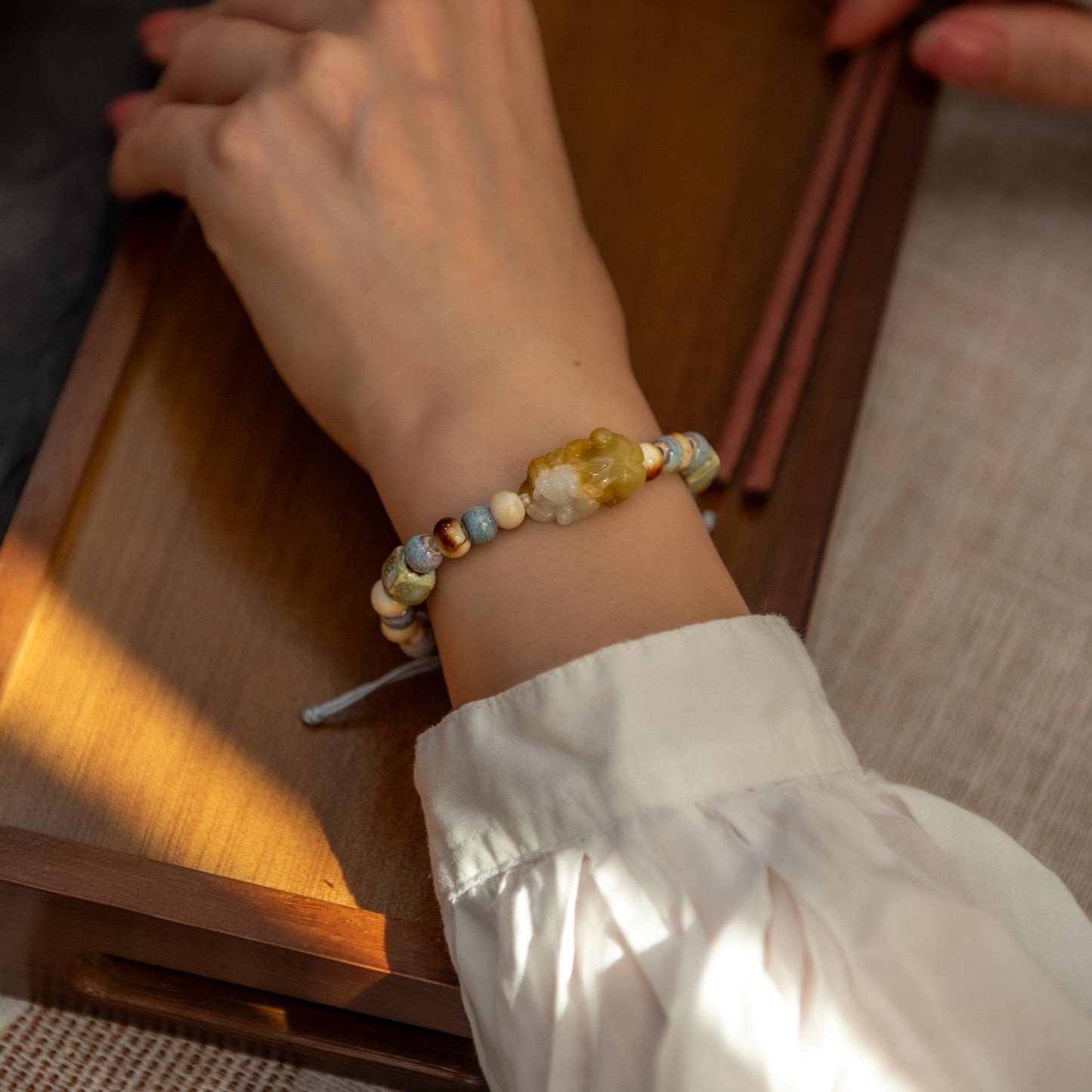 Close-up of a hand wearing a beaded bracelet on a wooden surface