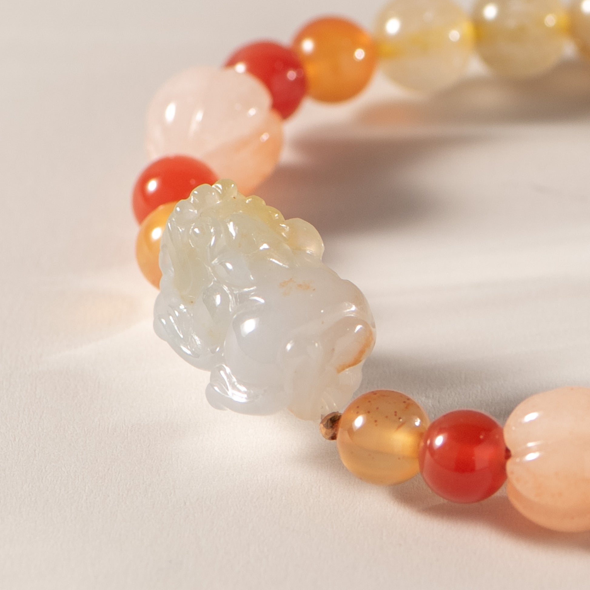 Bracelet with a jade pendant and multicolored beads on a light background