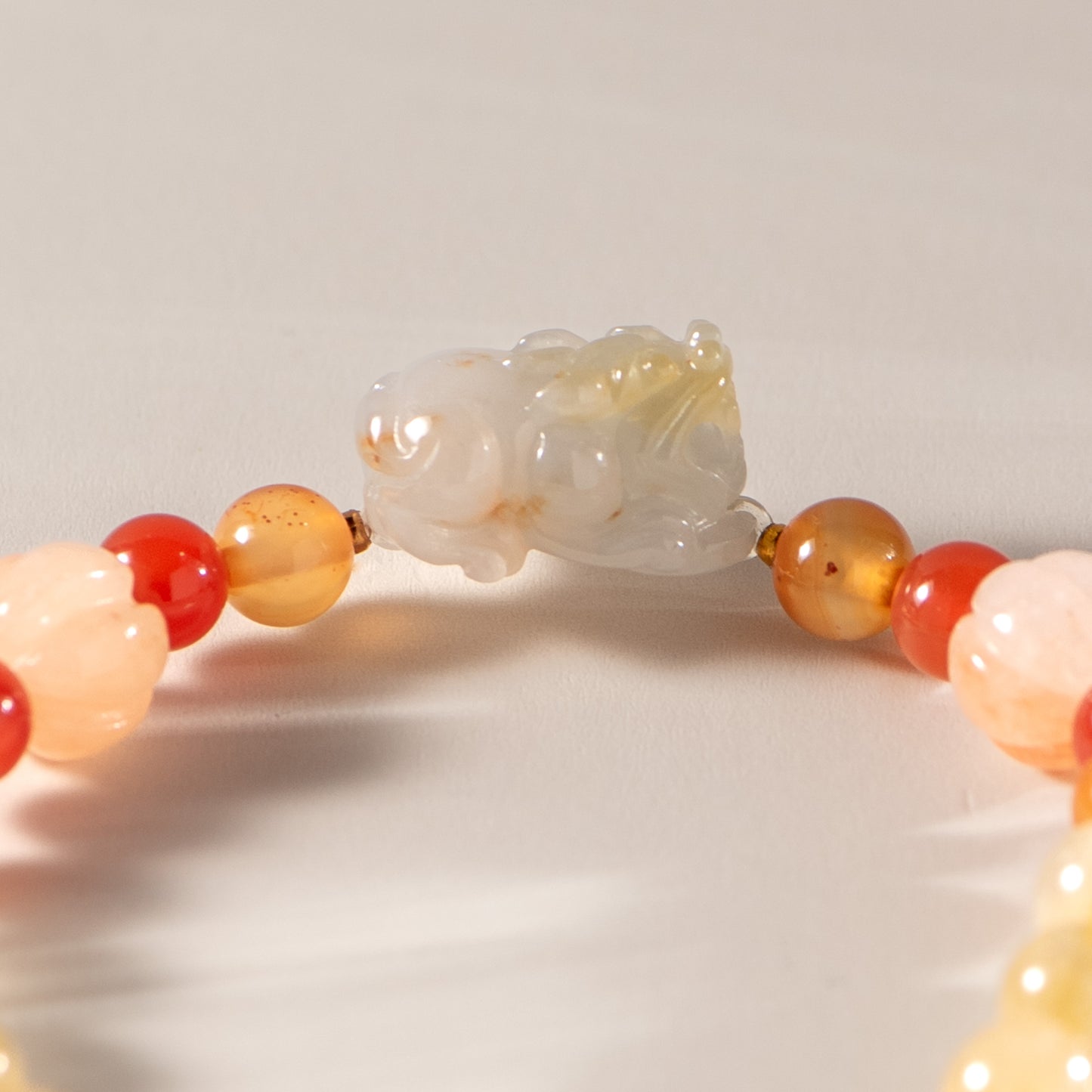 Close-up of a beaded bracelet with a white jade pendant on a light background