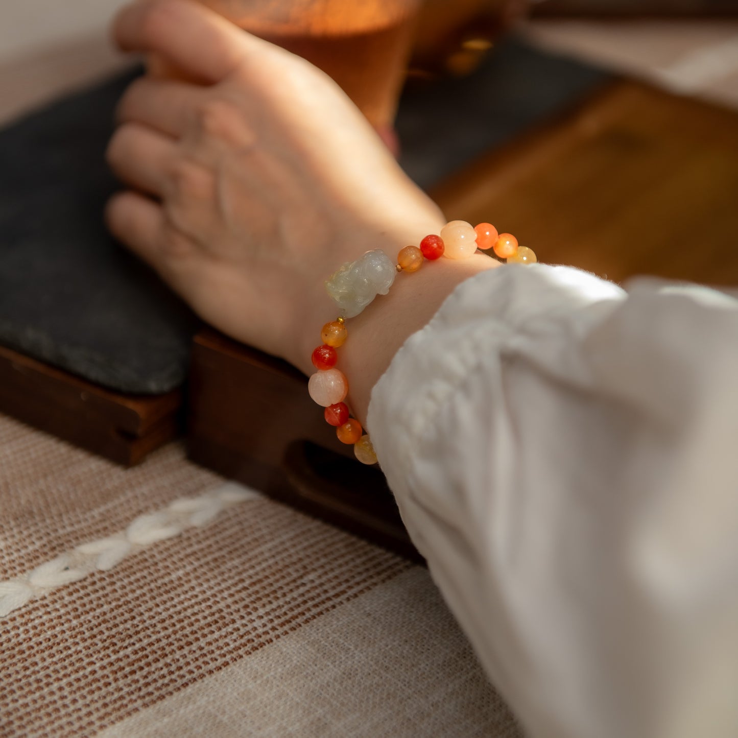 Close-up of a hand wearing a colorful beaded bracelet on a wooden surface.