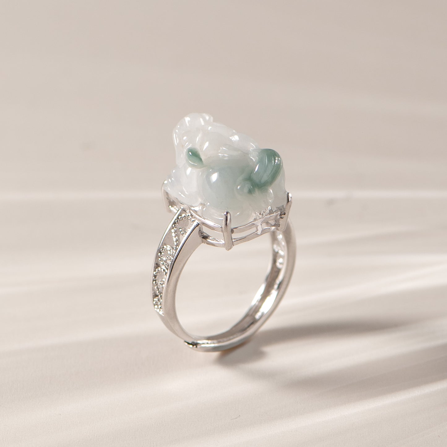 Silver ring with a green gemstone on a beige background