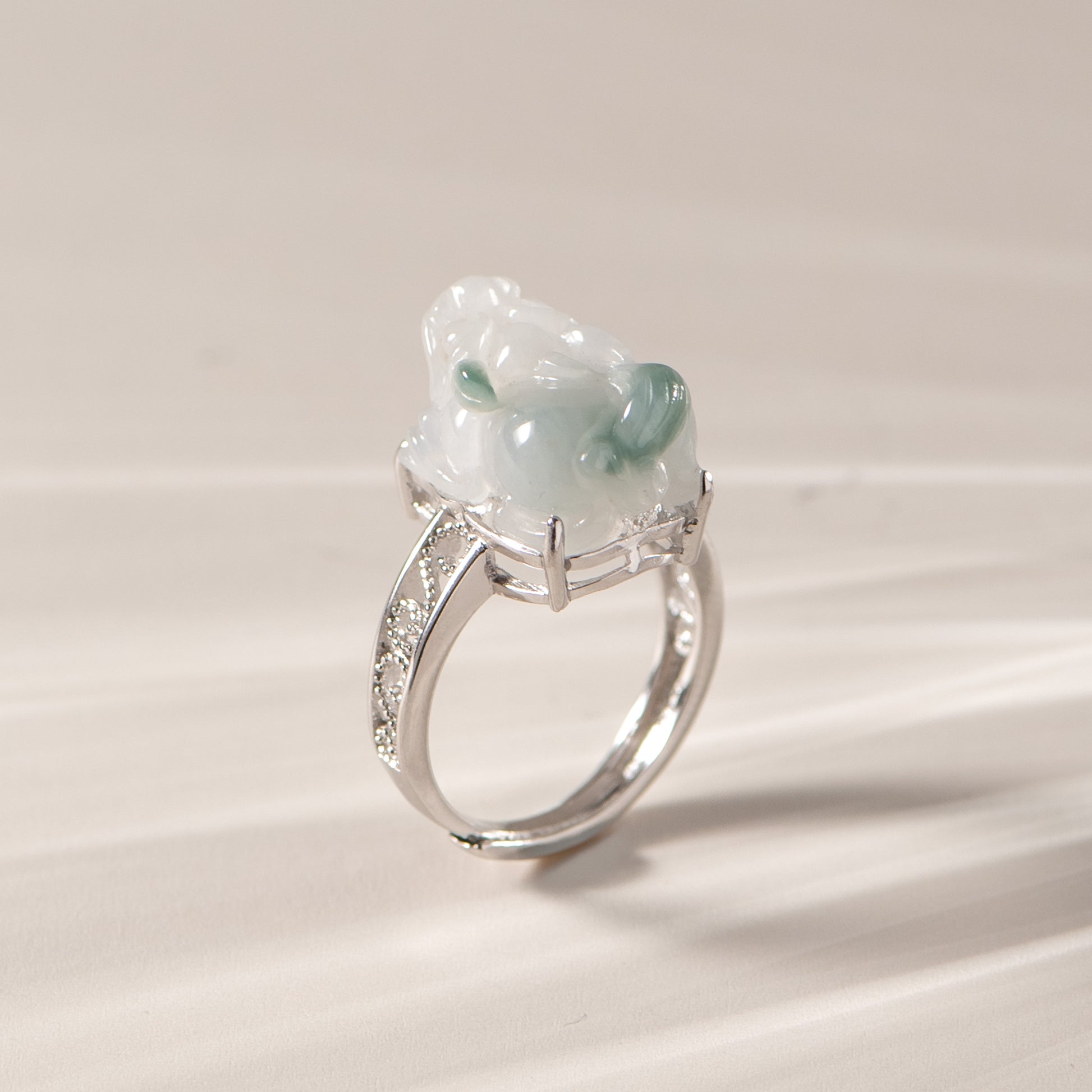 Silver ring with a green gemstone on a beige background