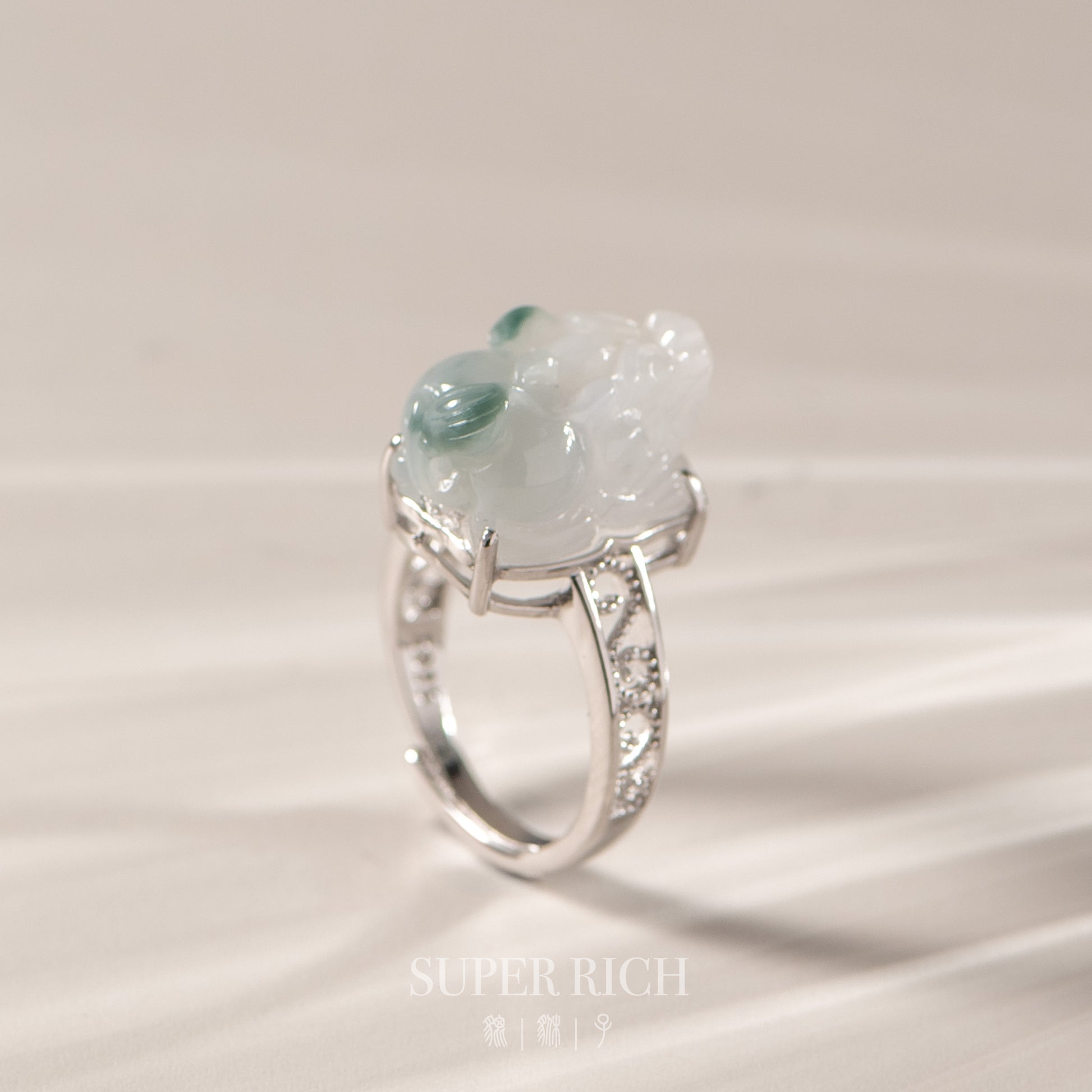 Silver ring with a green gemstone on a beige background