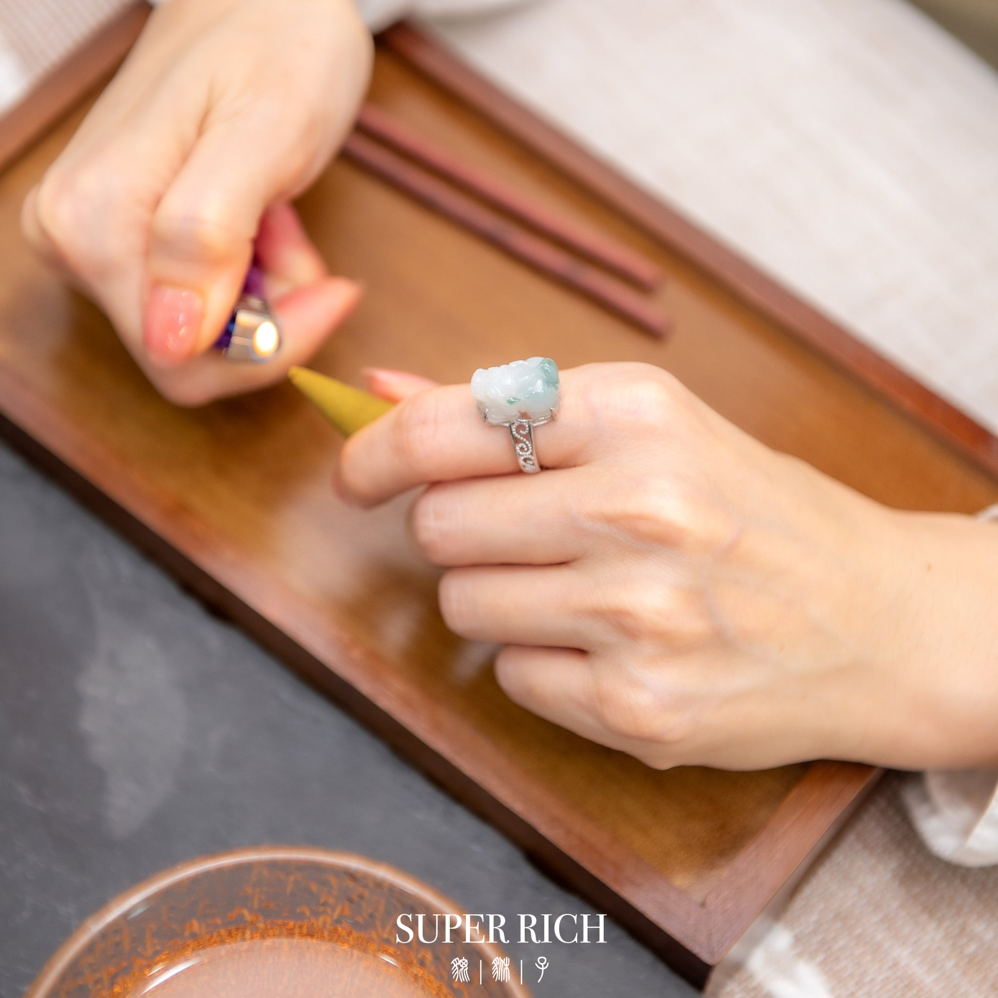 Person lighting a match with a ring on a wooden surface, 'SUPER RICH' brand visible.