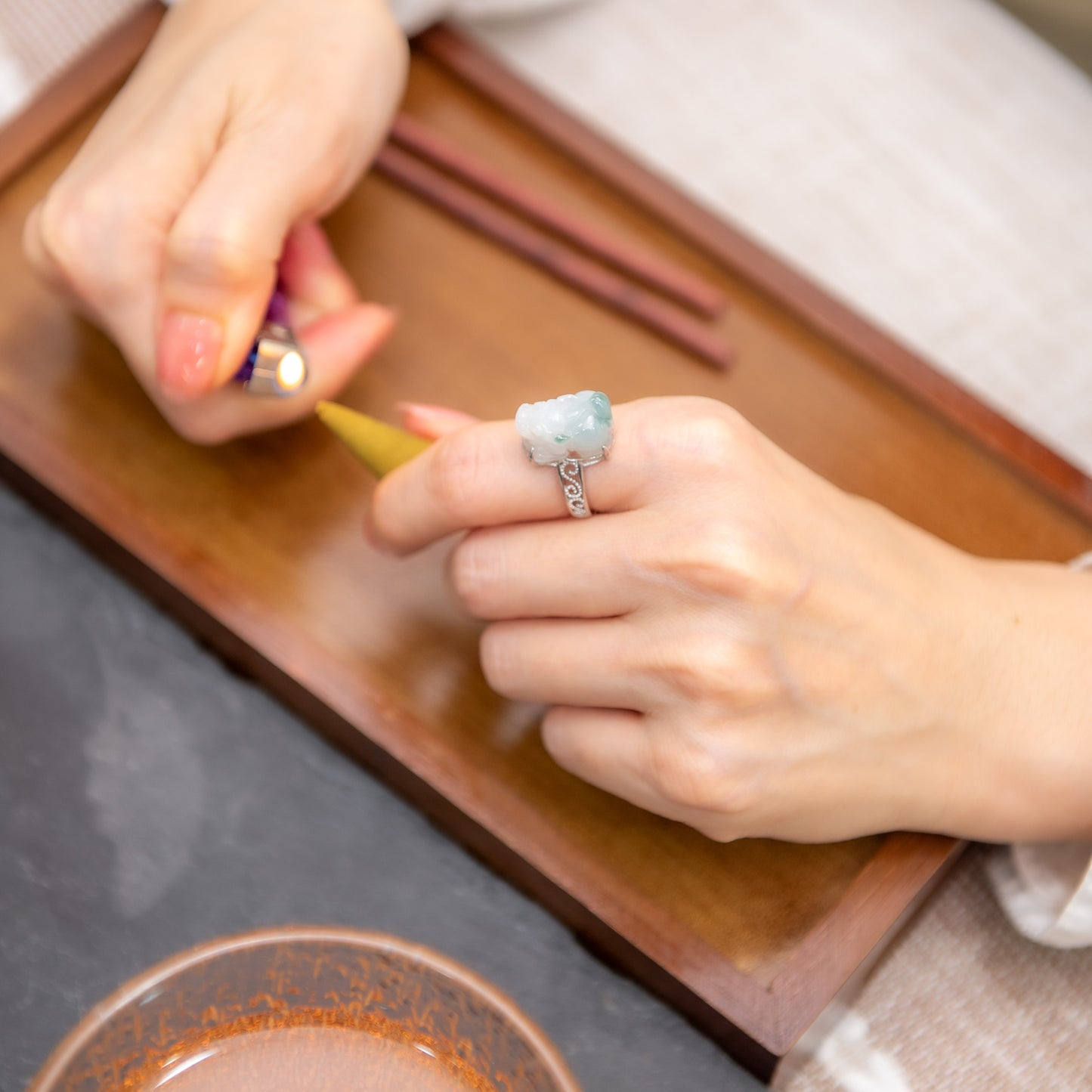 Person lighting a match with a ring on their finger, sitting at a table.