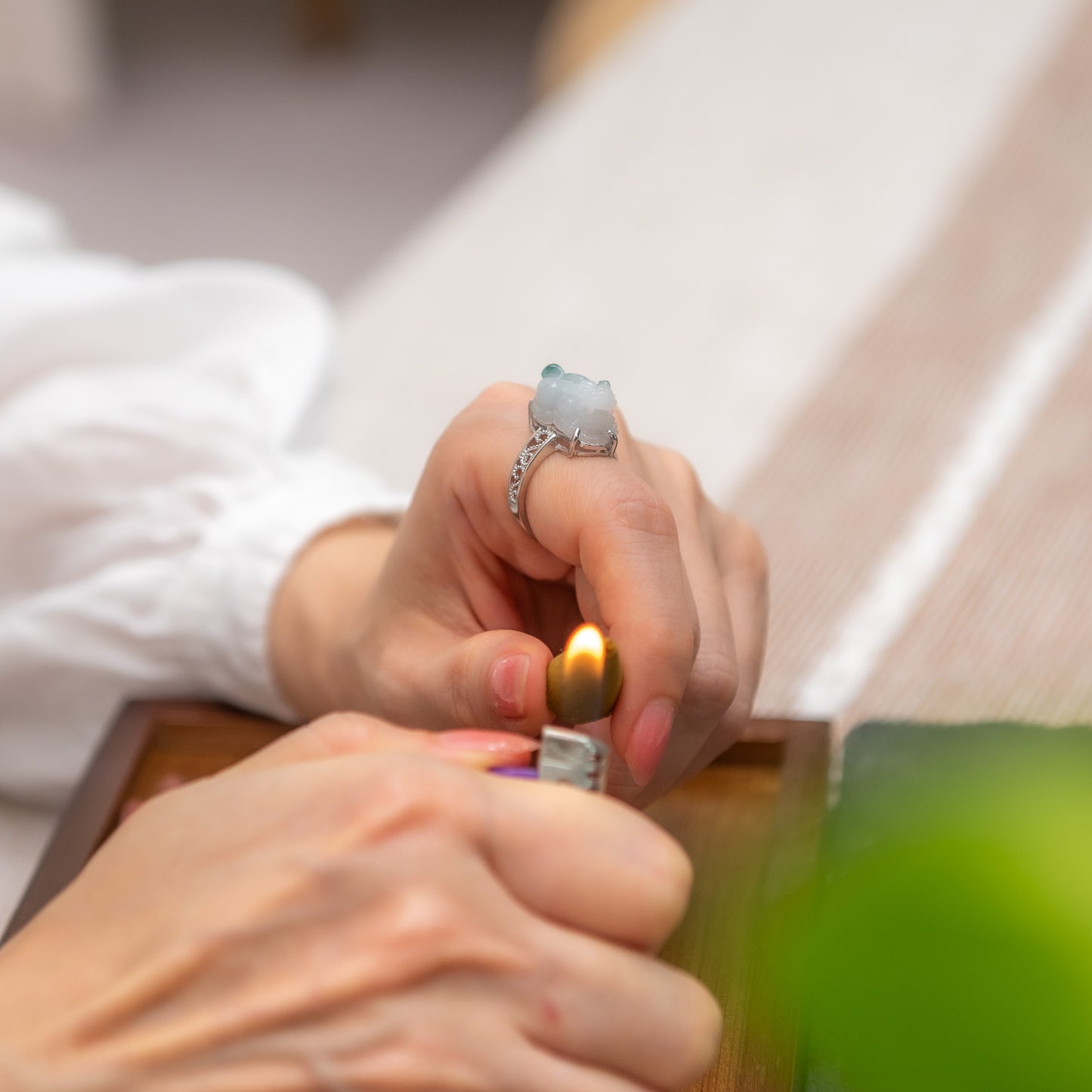 Close-up of hands lighting a candle with a lighter.