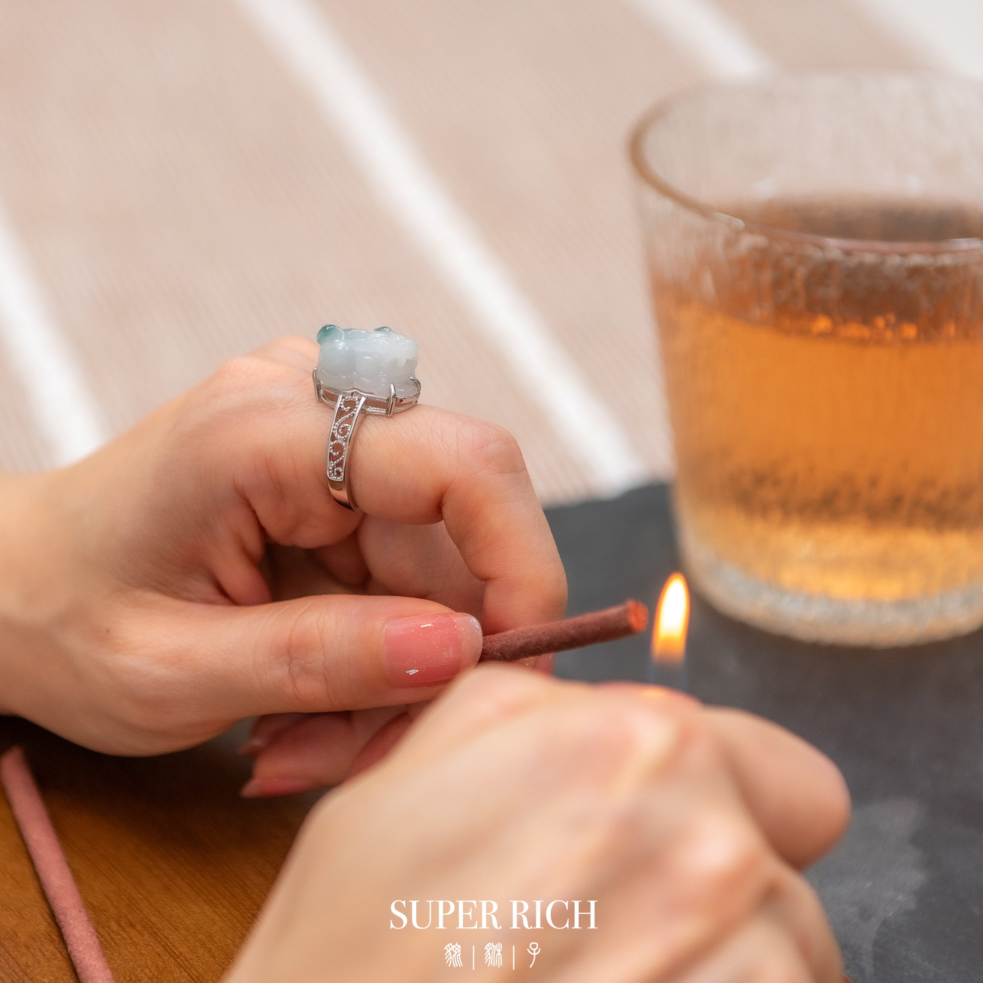 Person lighting a match with a glass of tea in the background
