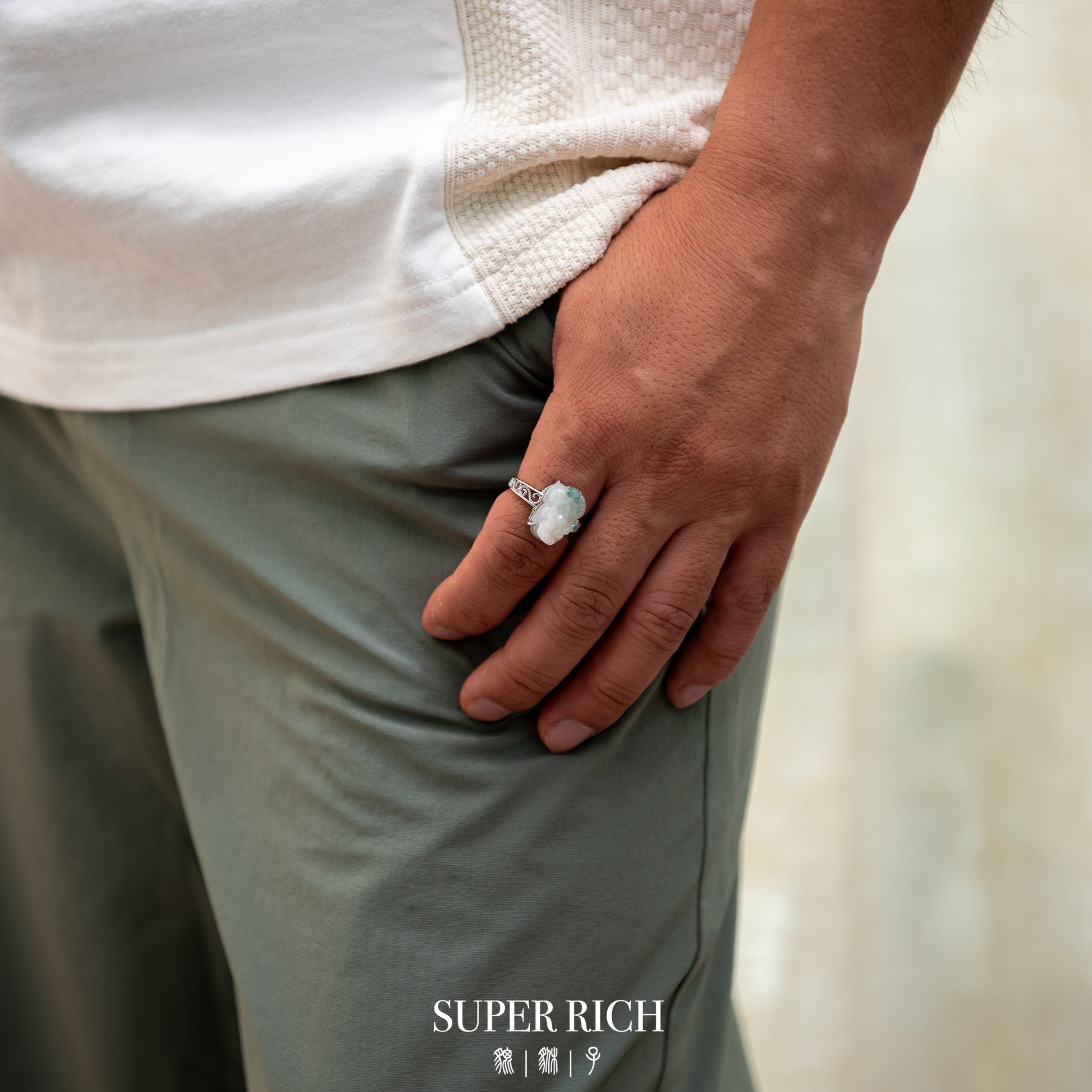 Person wearing a ring with a large stone, holding a white towel, on a blurred background.