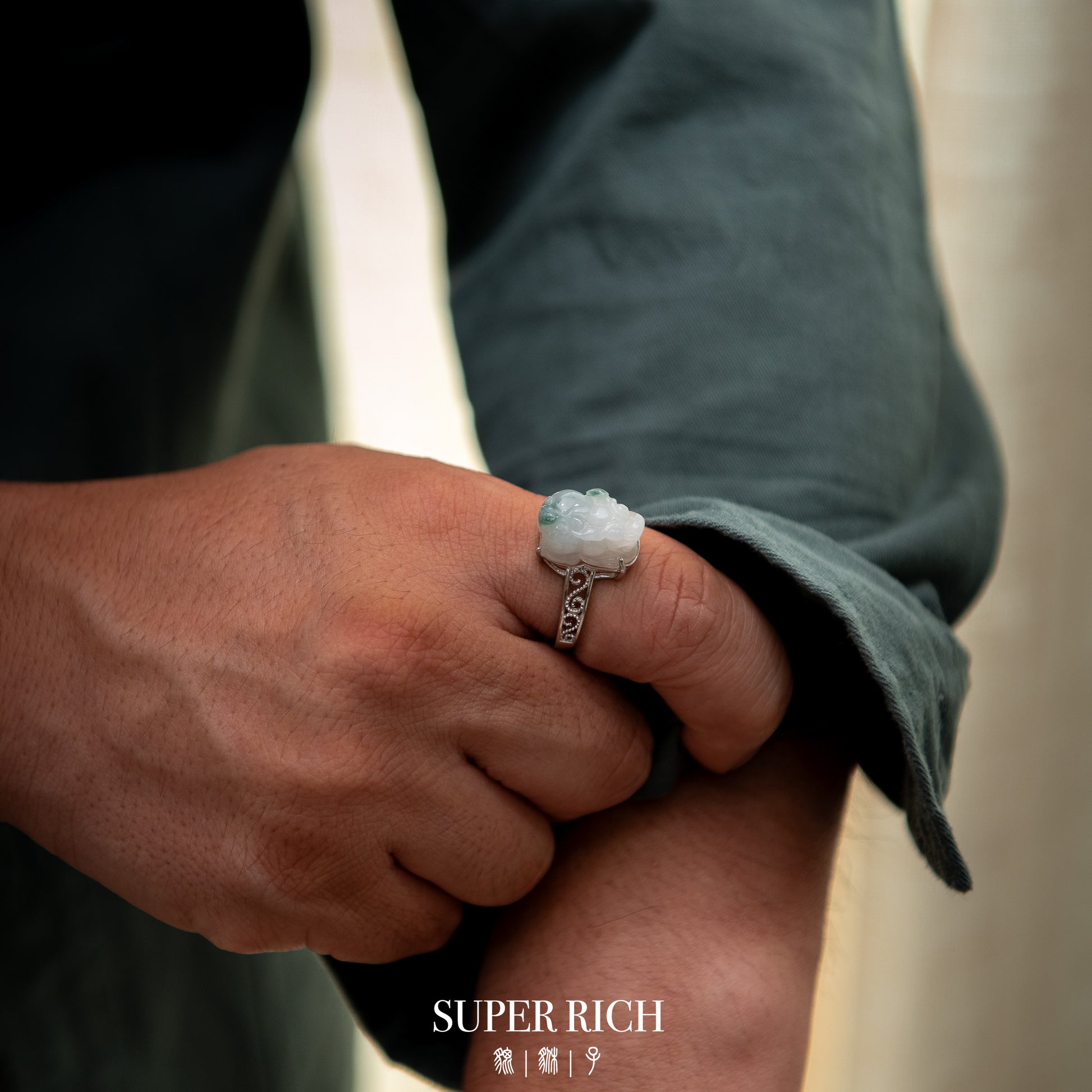 Hand wearing a ring with a decorative stone, blurred background