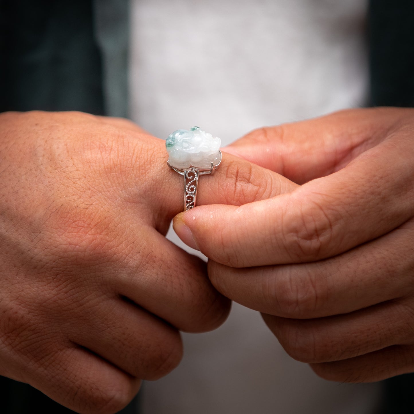 Close-up of hands holding a silver ring with a gemstone