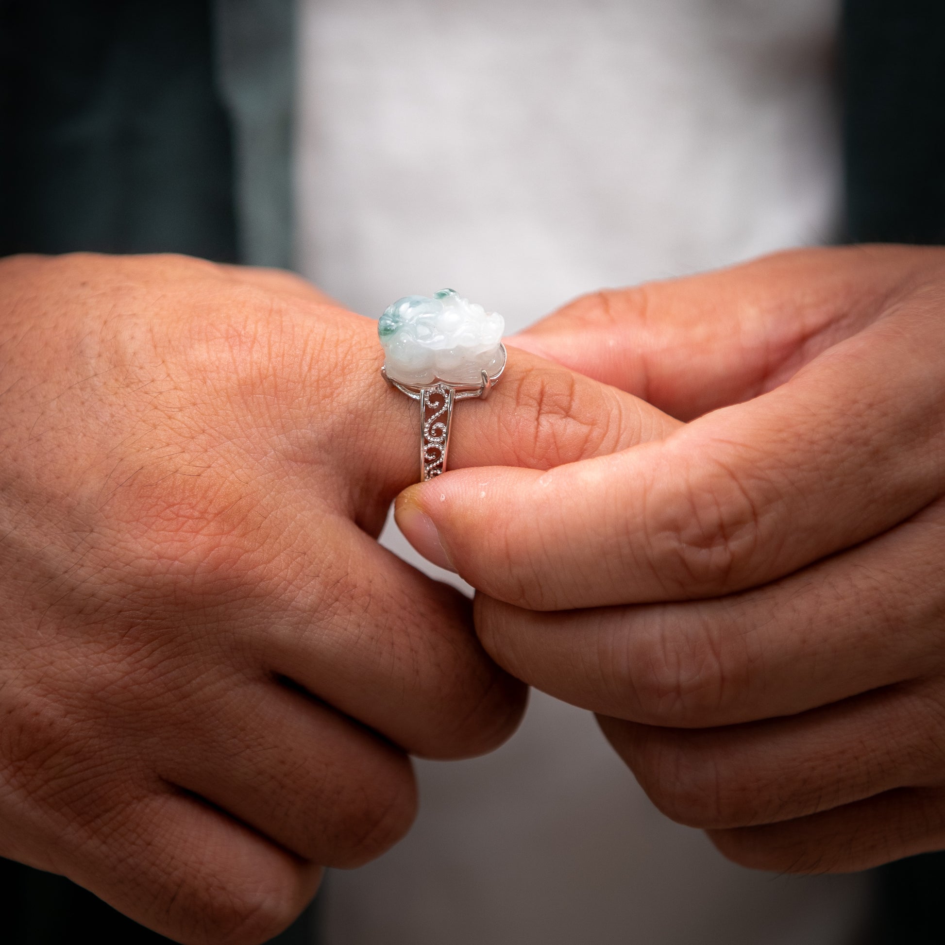 Close-up of hands holding a silver ring with a gemstone