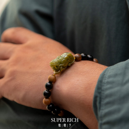 Close-up of a wrist wearing a beaded bracelet with a green stone, against a blurred background.