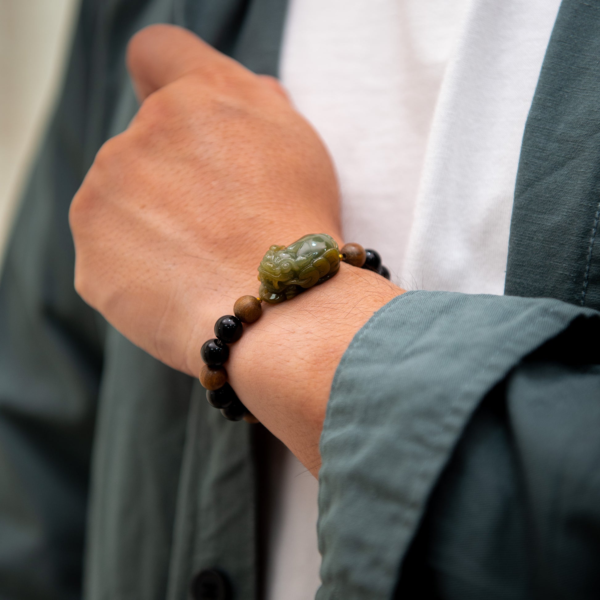 Close-up of a hand wearing a bracelet with a green stone and black beads.