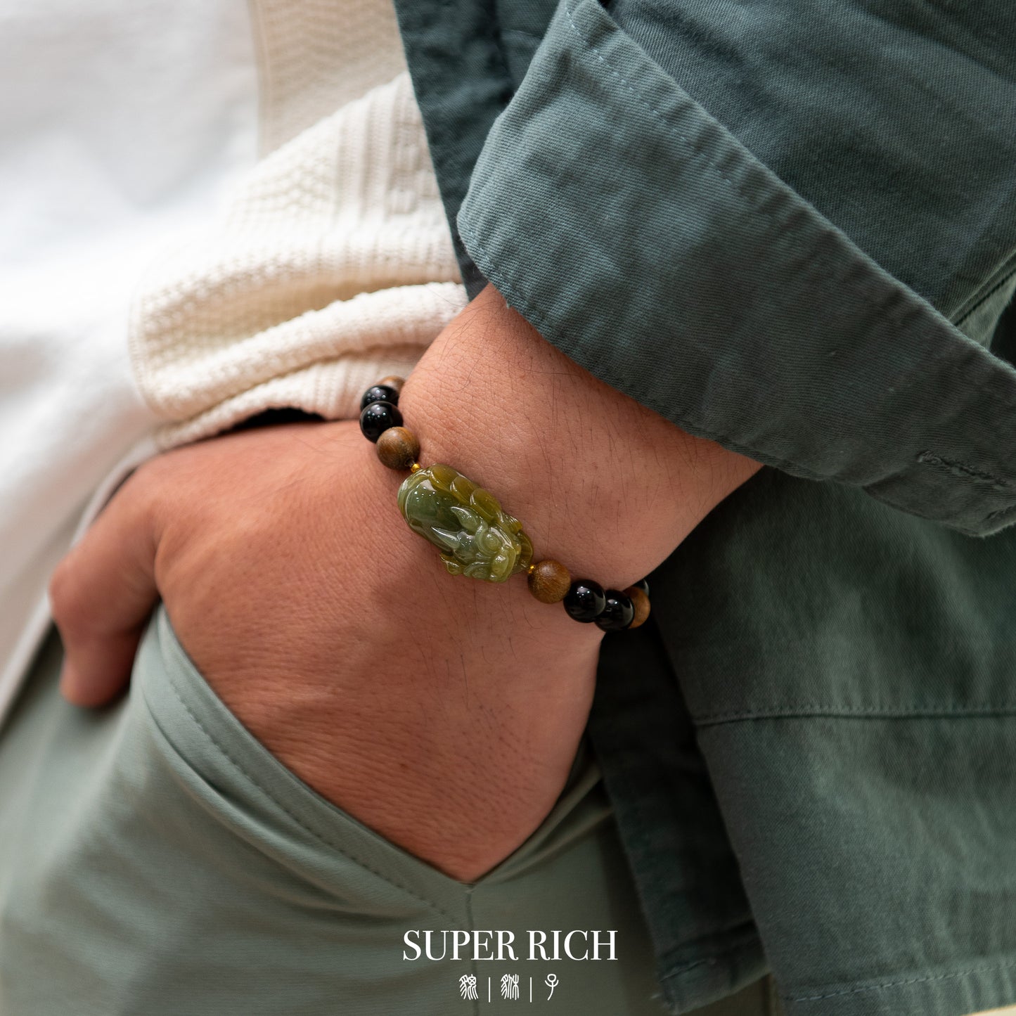 Person wearing a bracelet with green and black beads on a neutral background