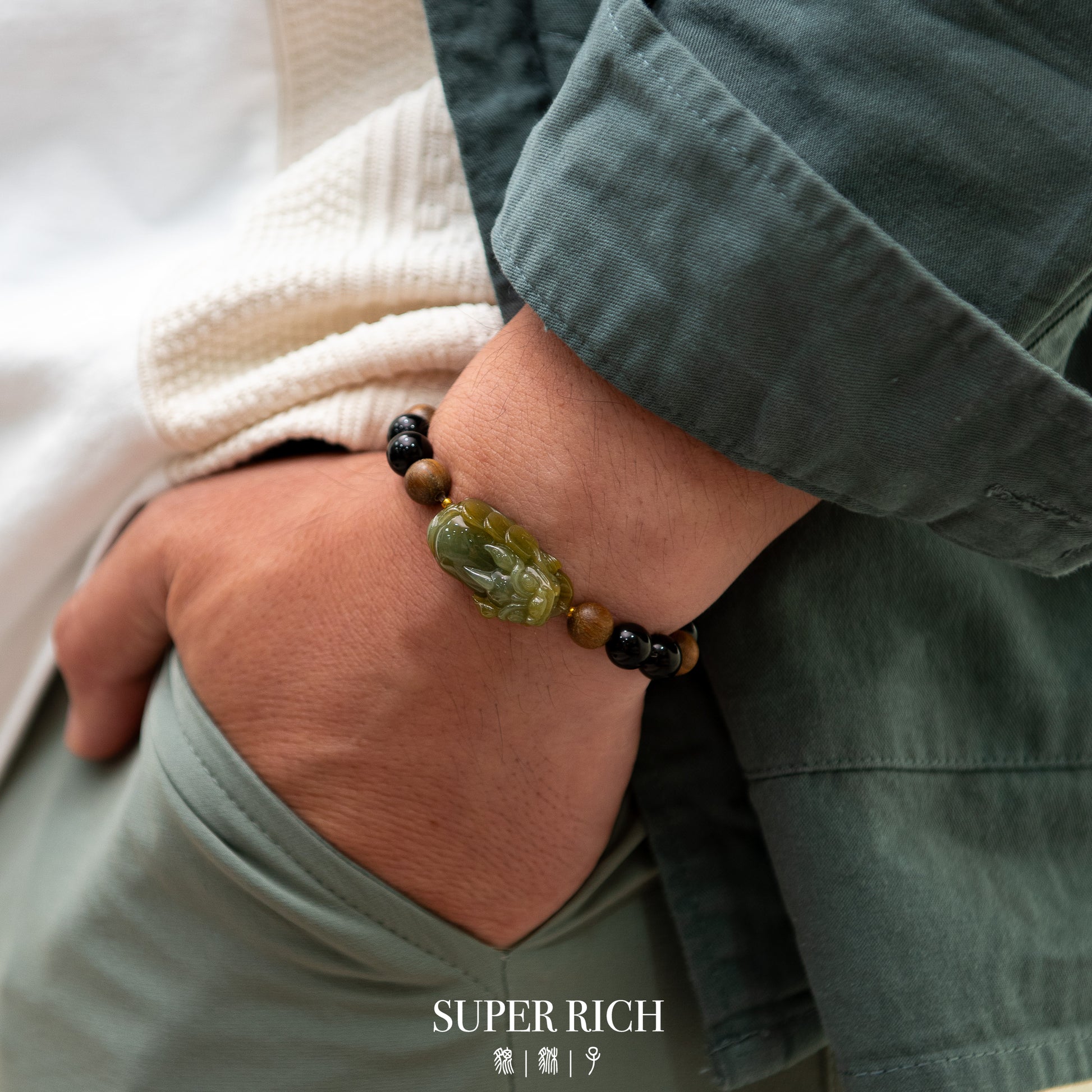 Person wearing a bracelet with green and black beads on a neutral background