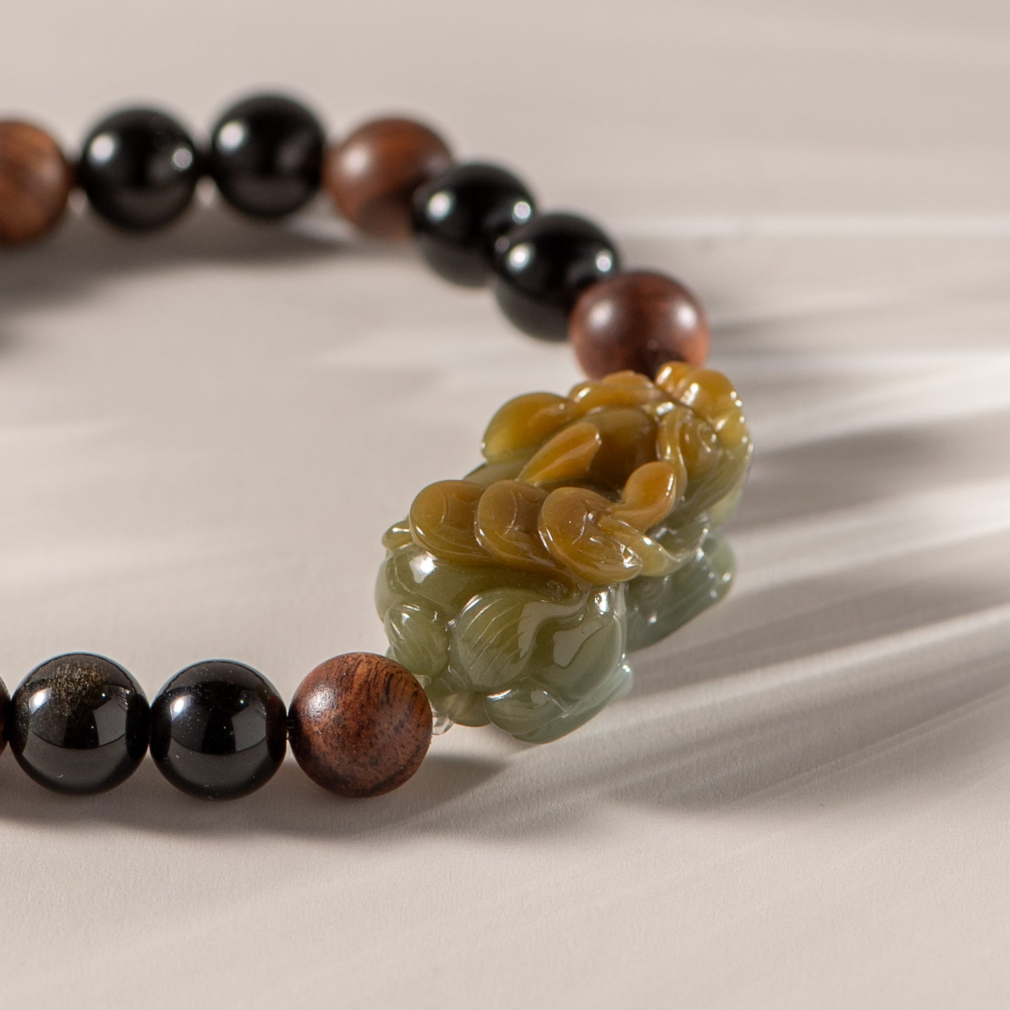 Bracelet with black, brown, and green beads on a beige background