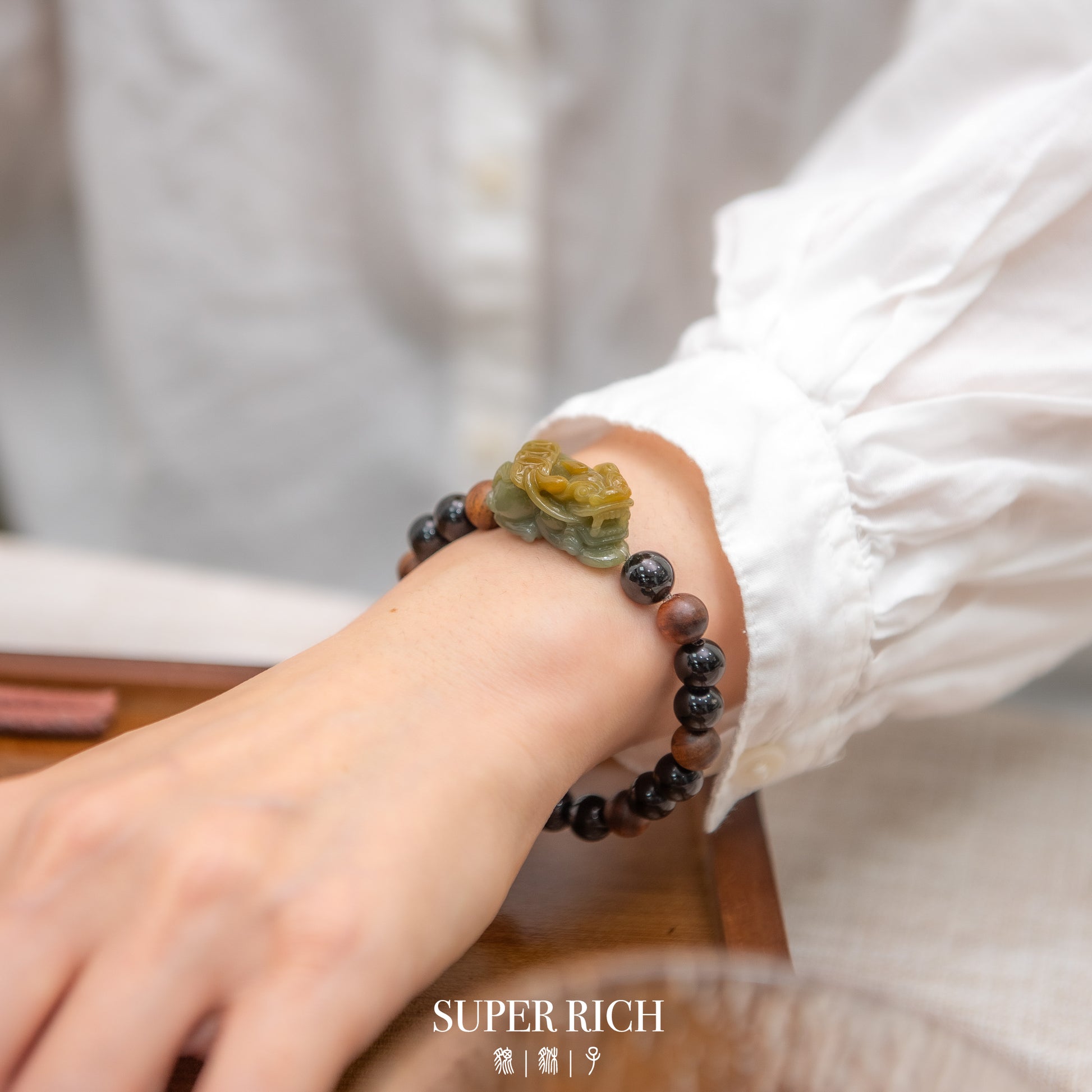 Close-up of a hand wearing a beaded bracelet with 'SUPER RICH' branding.