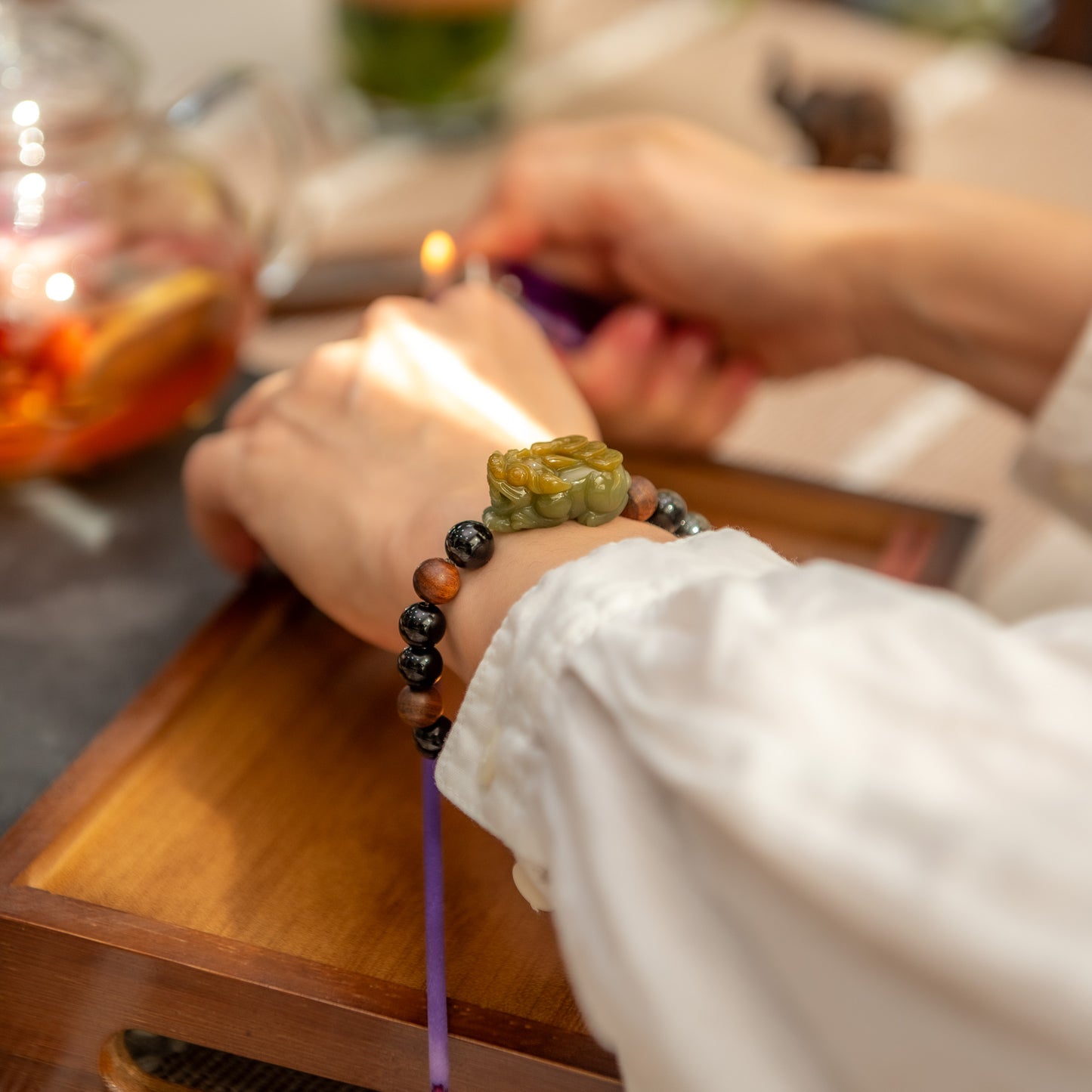 Person wearing a colorful beaded bracelet on a wooden surface with a blurred background