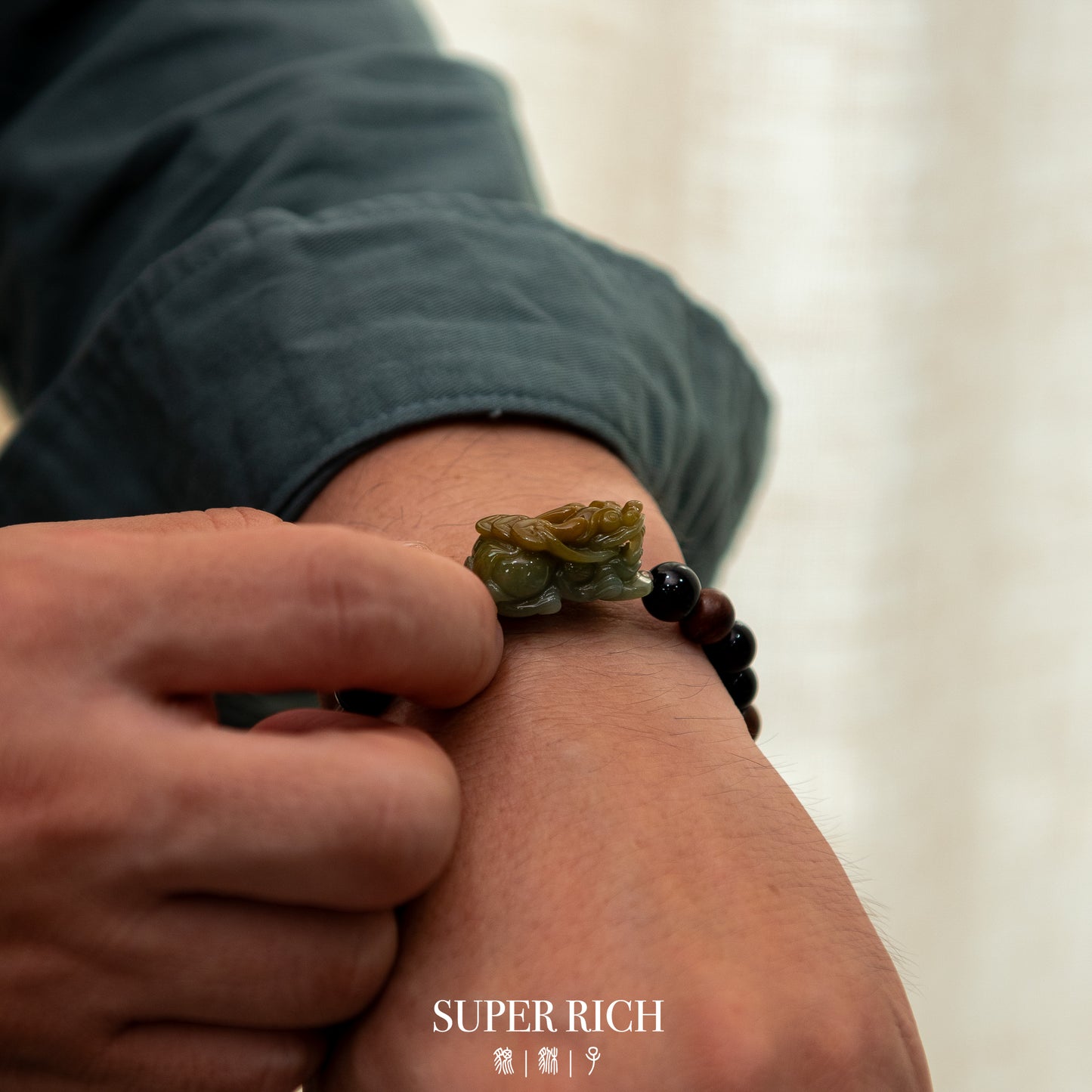 Person wearing a green jade bracelet on a blurred background with 'SUPER RICH' branding.