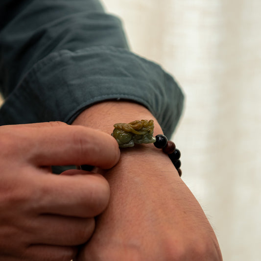 Close-up of a hand wearing a bracelet with a small figurine on a blurred background