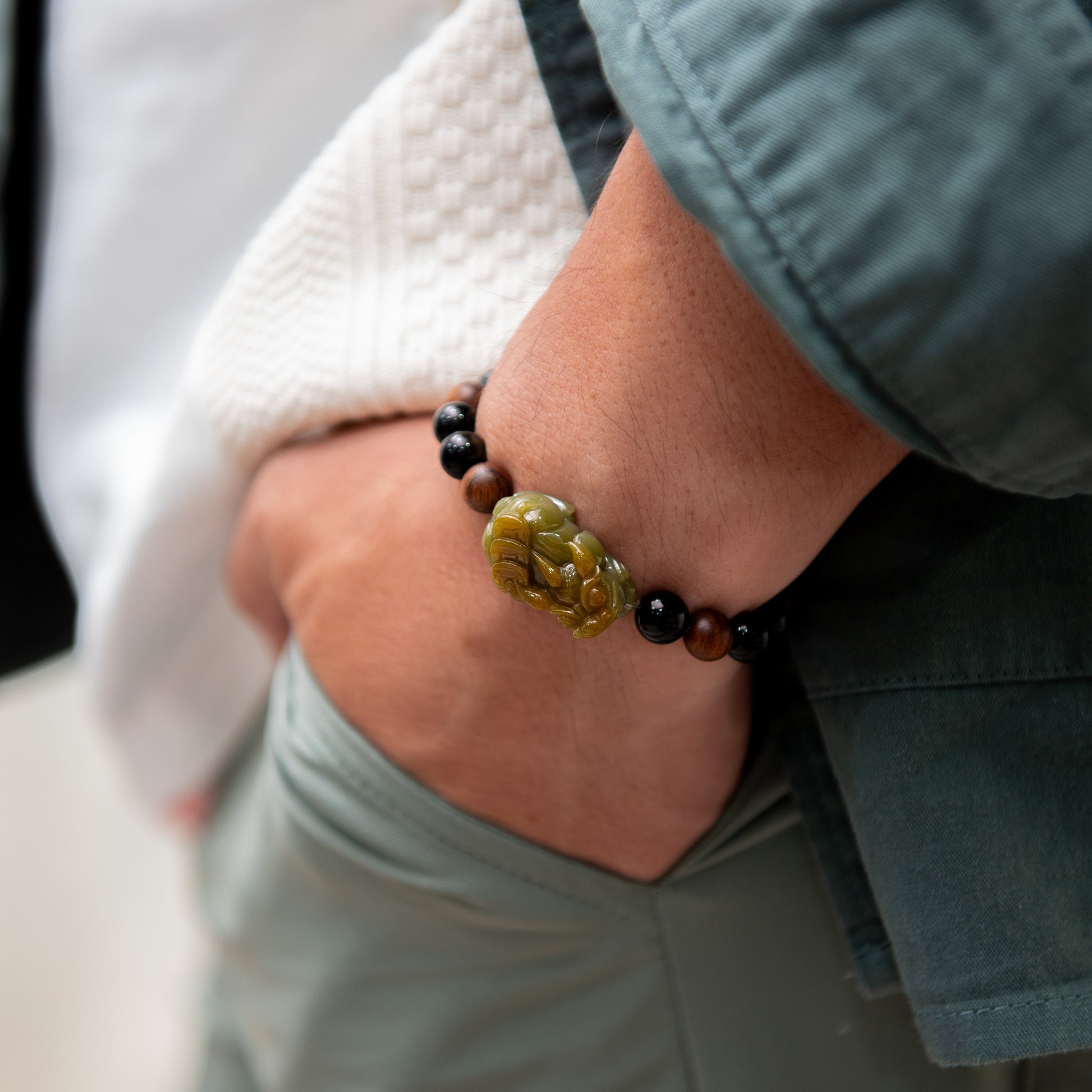 Close-up of a wrist wearing a bracelet with a green stone and black beads.