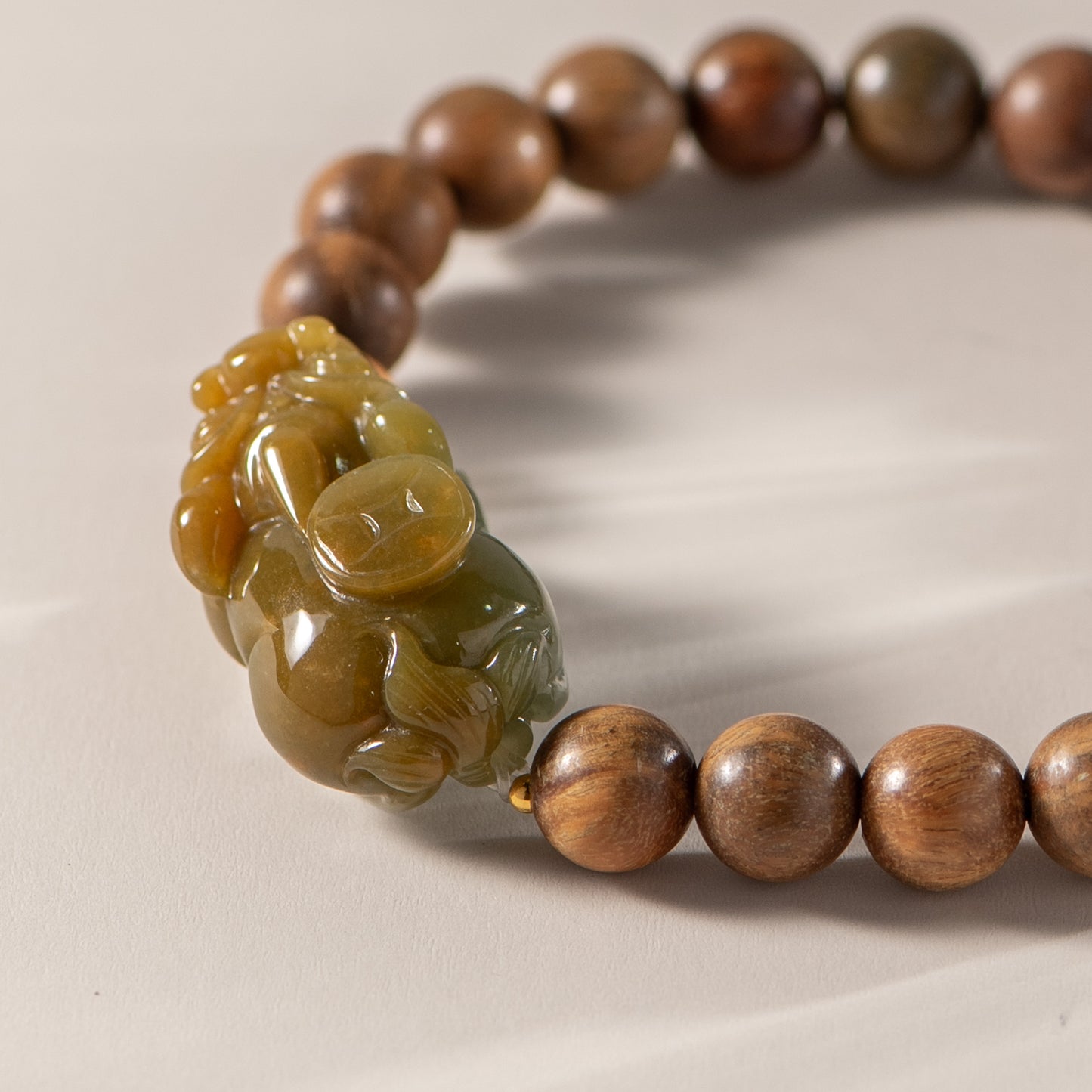 Wooden beaded bracelet with a carved stone pendant on a beige background