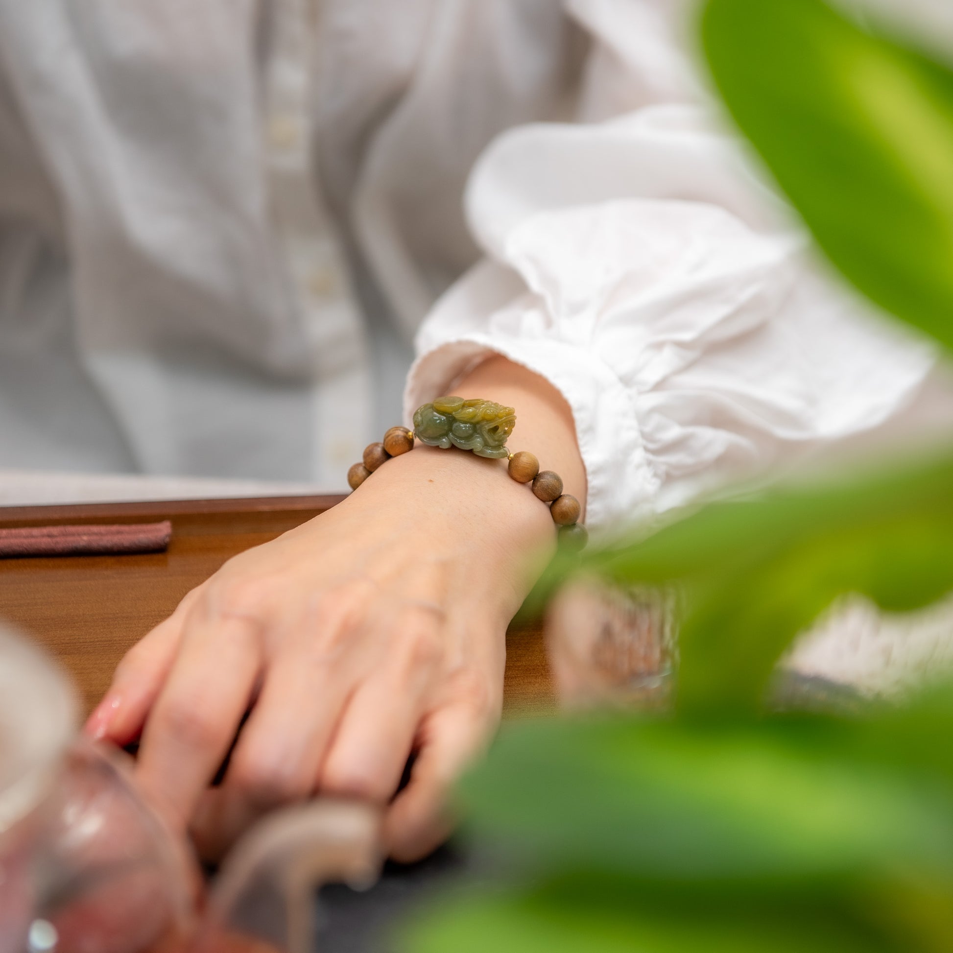 Person wearing a bracelet with green stones on a blurred background