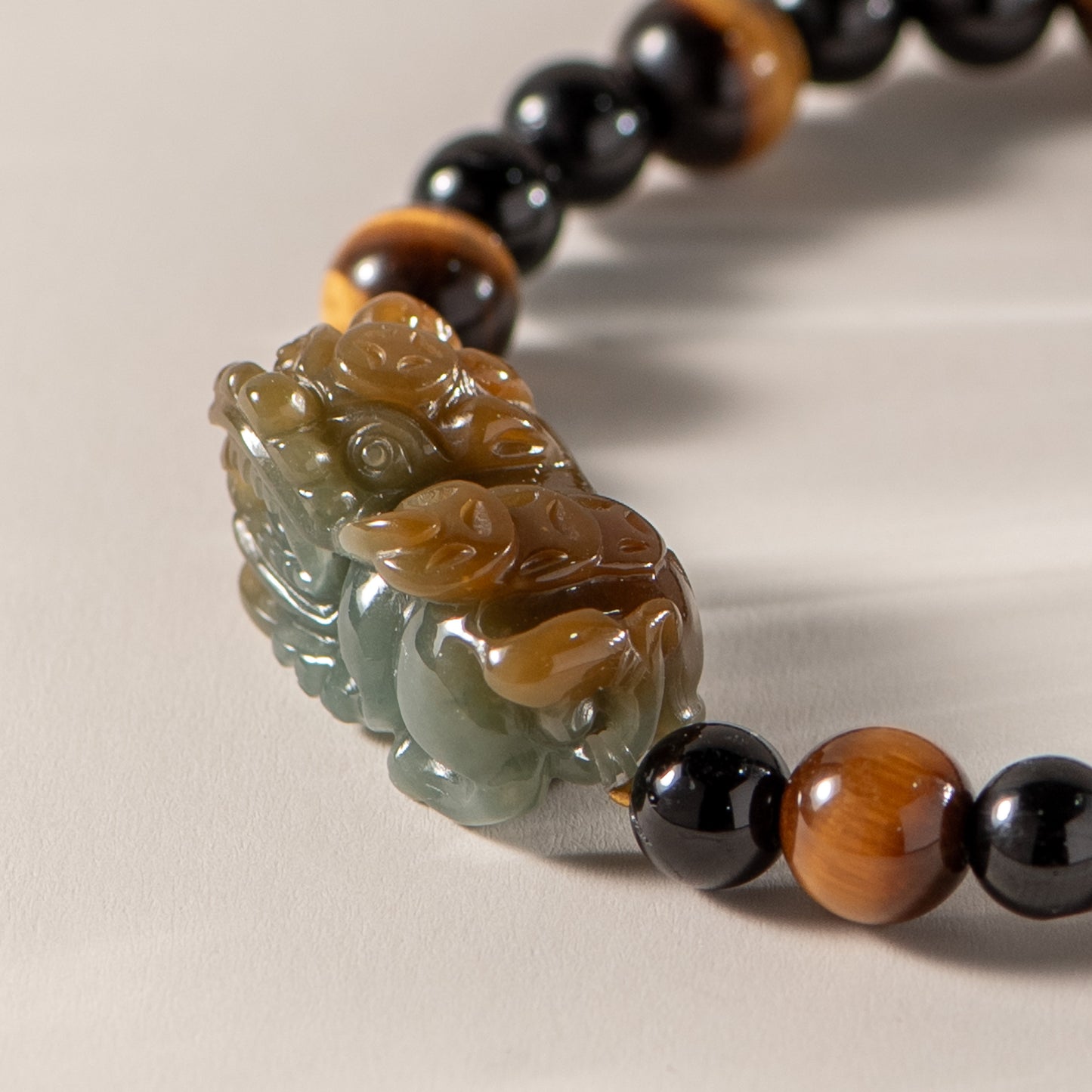 Close-up of a beaded bracelet with a carved stone pendant on a neutral background