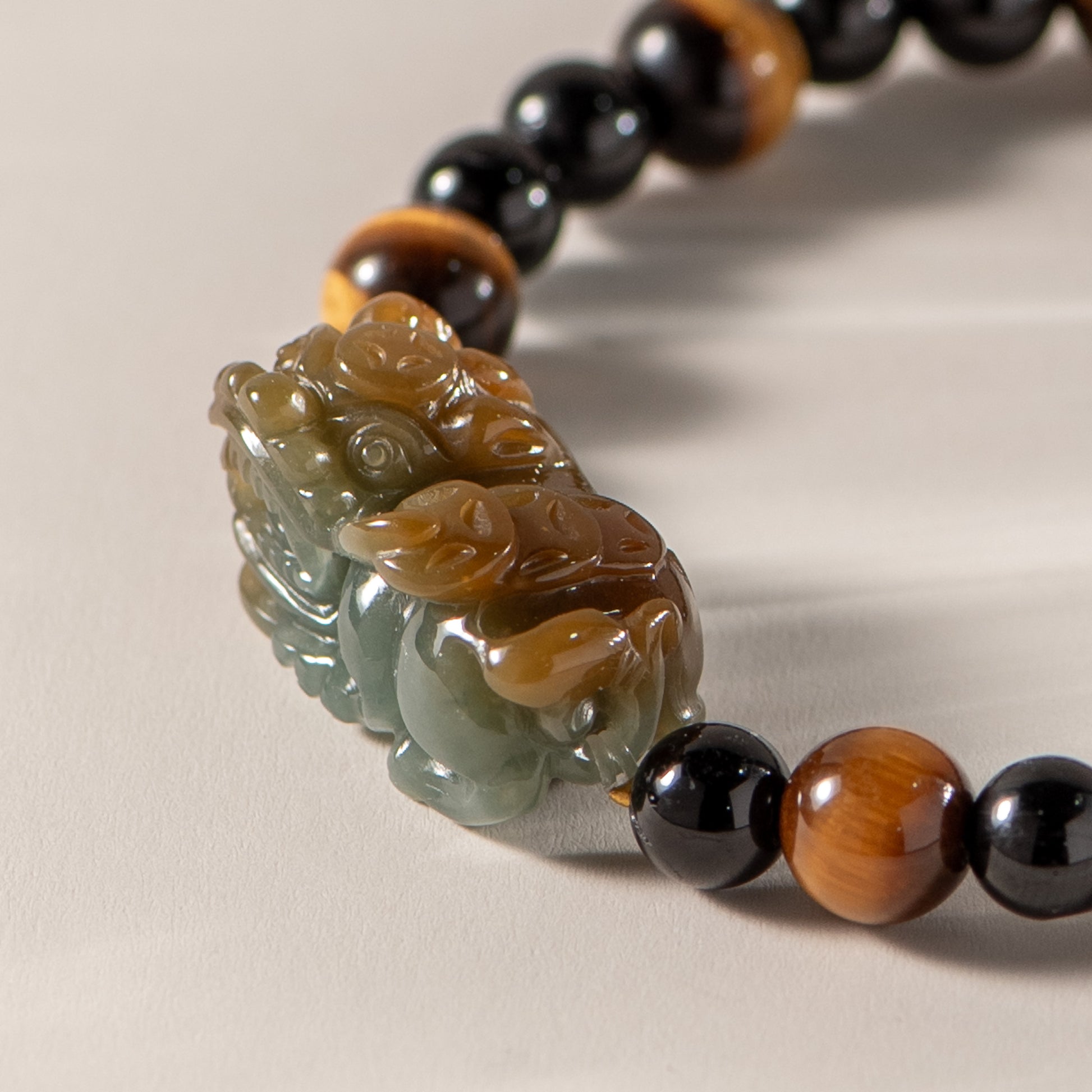 Close-up of a beaded bracelet with a carved stone pendant on a neutral background
