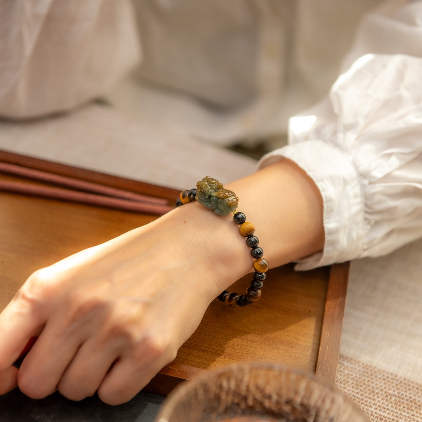 Person wearing a beaded bracelet on a wooden table