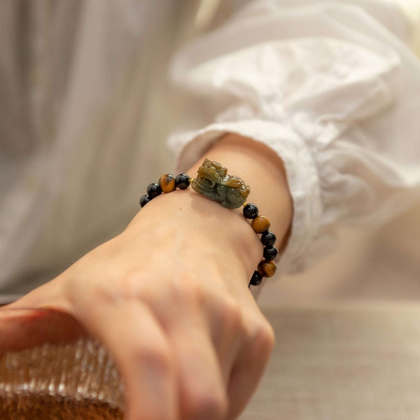 Close-up of a hand wearing a bracelet with natural stone beads on a neutral background