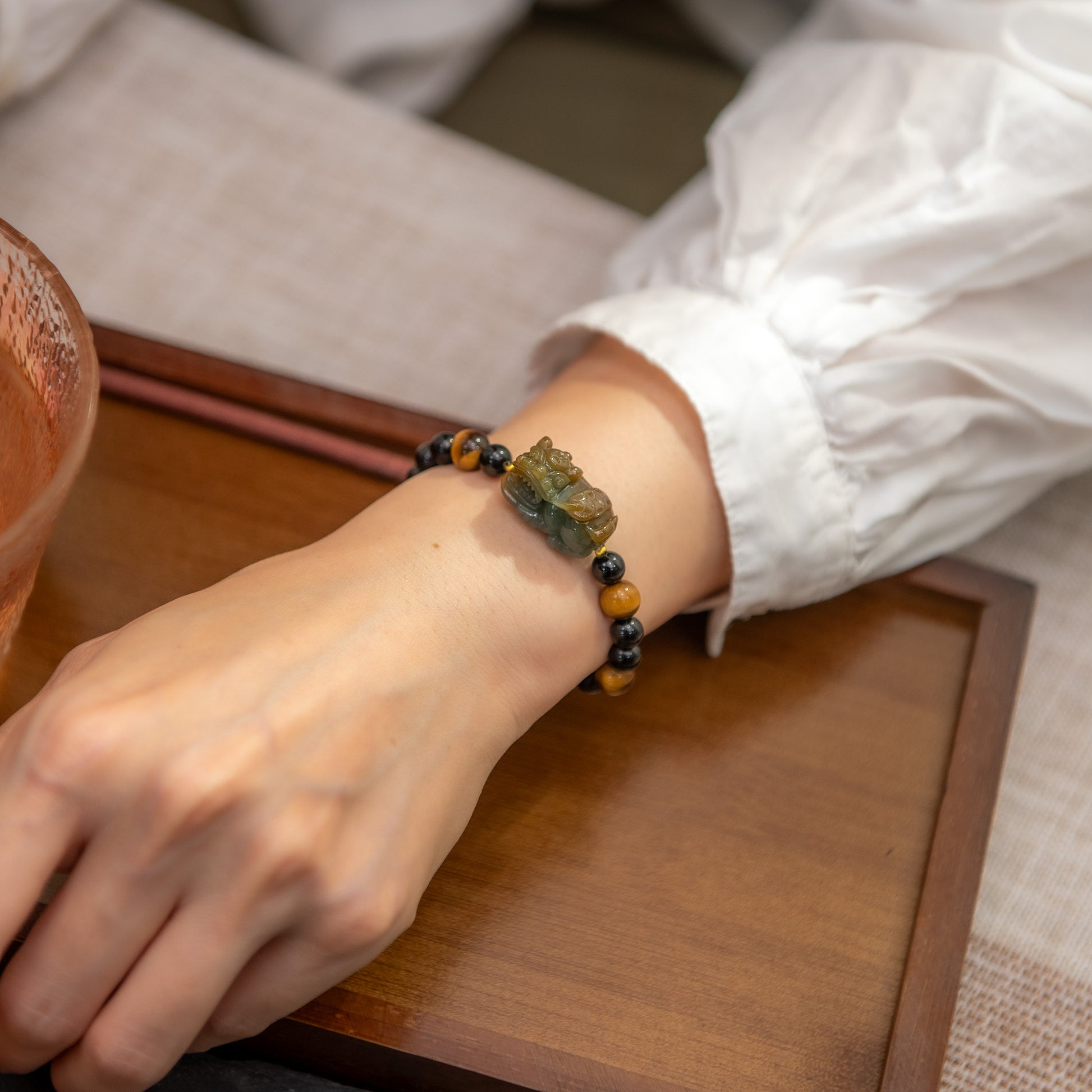 Person wearing a beaded bracelet on a wooden surface