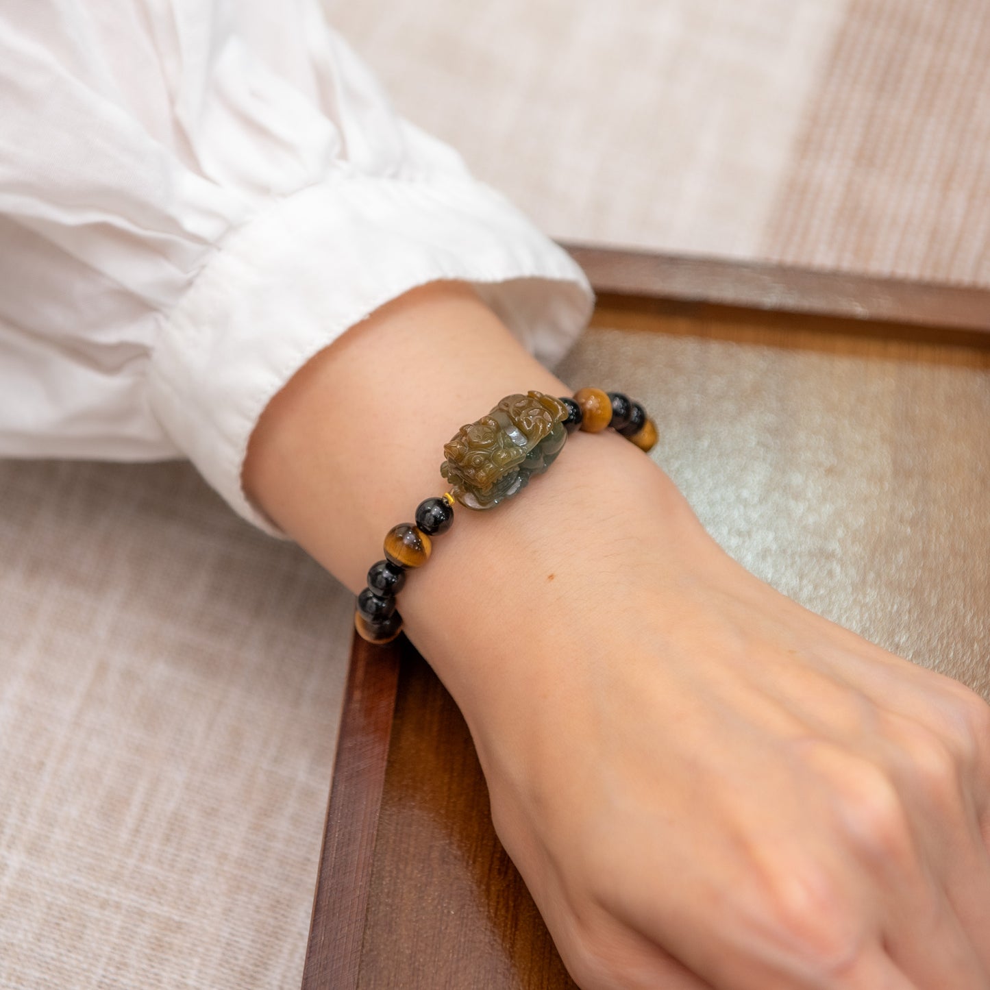 Close-up of a wrist wearing a beaded bracelet with a decorative clasp on a neutral background