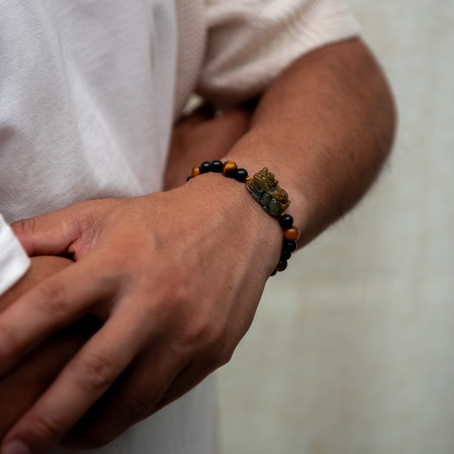 Close-up of a wrist wearing a beaded bracelet with a neutral background