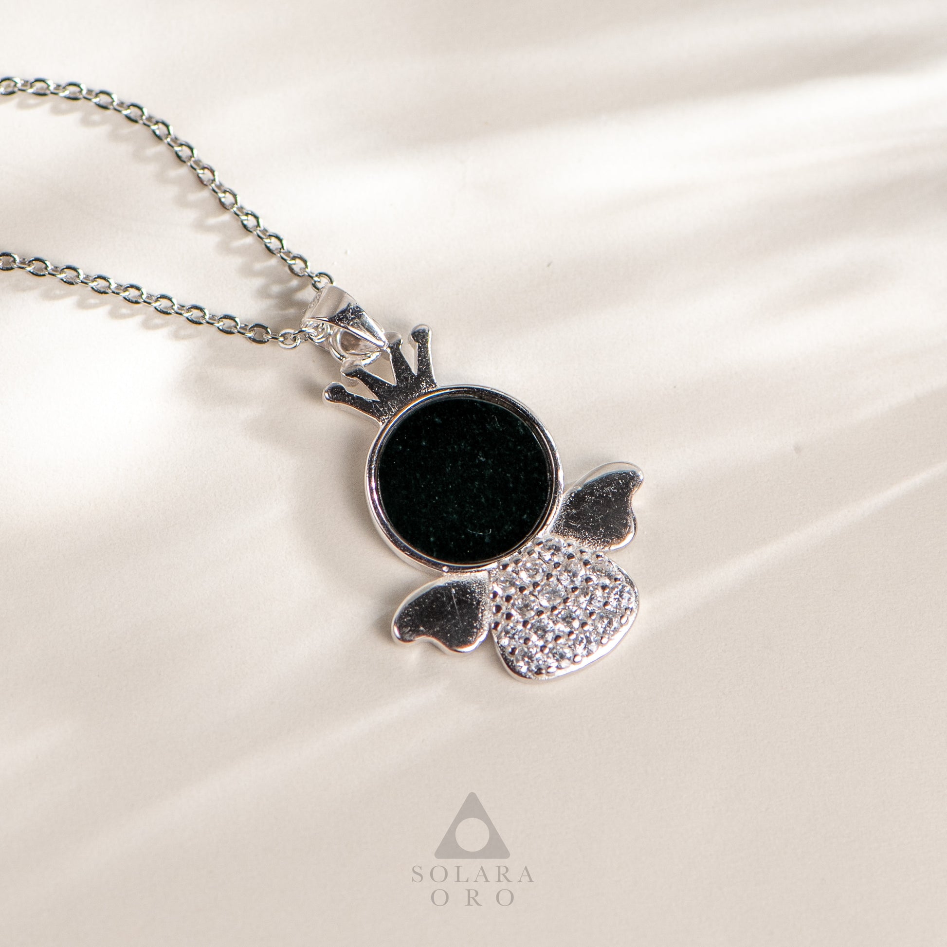 Silver necklace with a black pendant on a white background