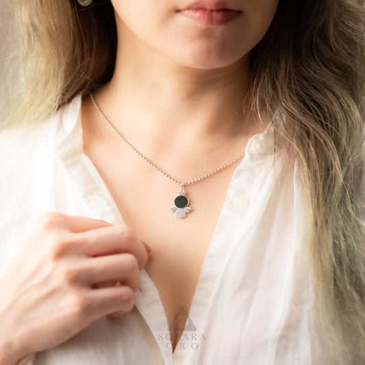 Necklace with a black pendant worn by a person, brand 'Suzanna' visible