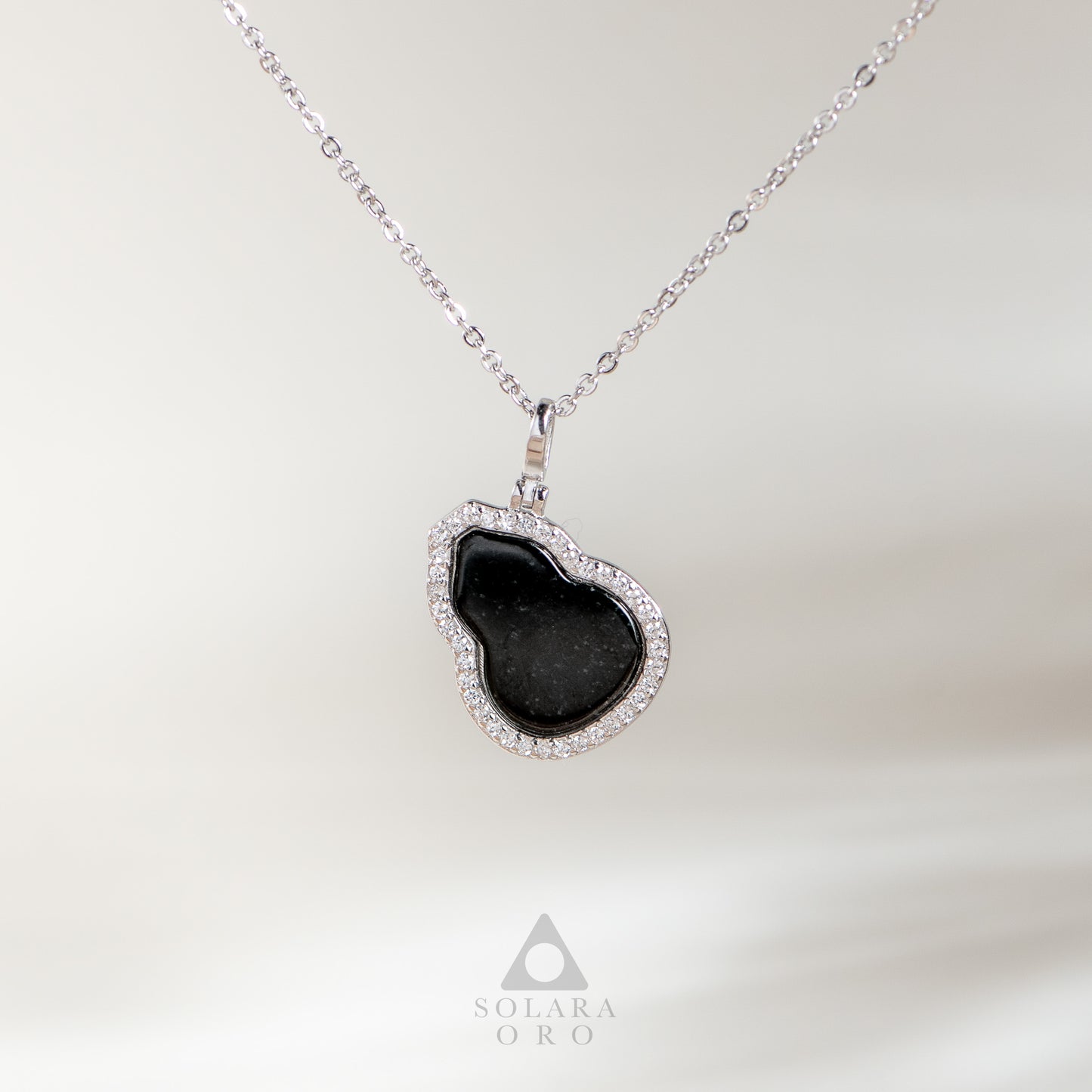 Heart-shaped black pendant necklace on a white background with Solara Oro logo.