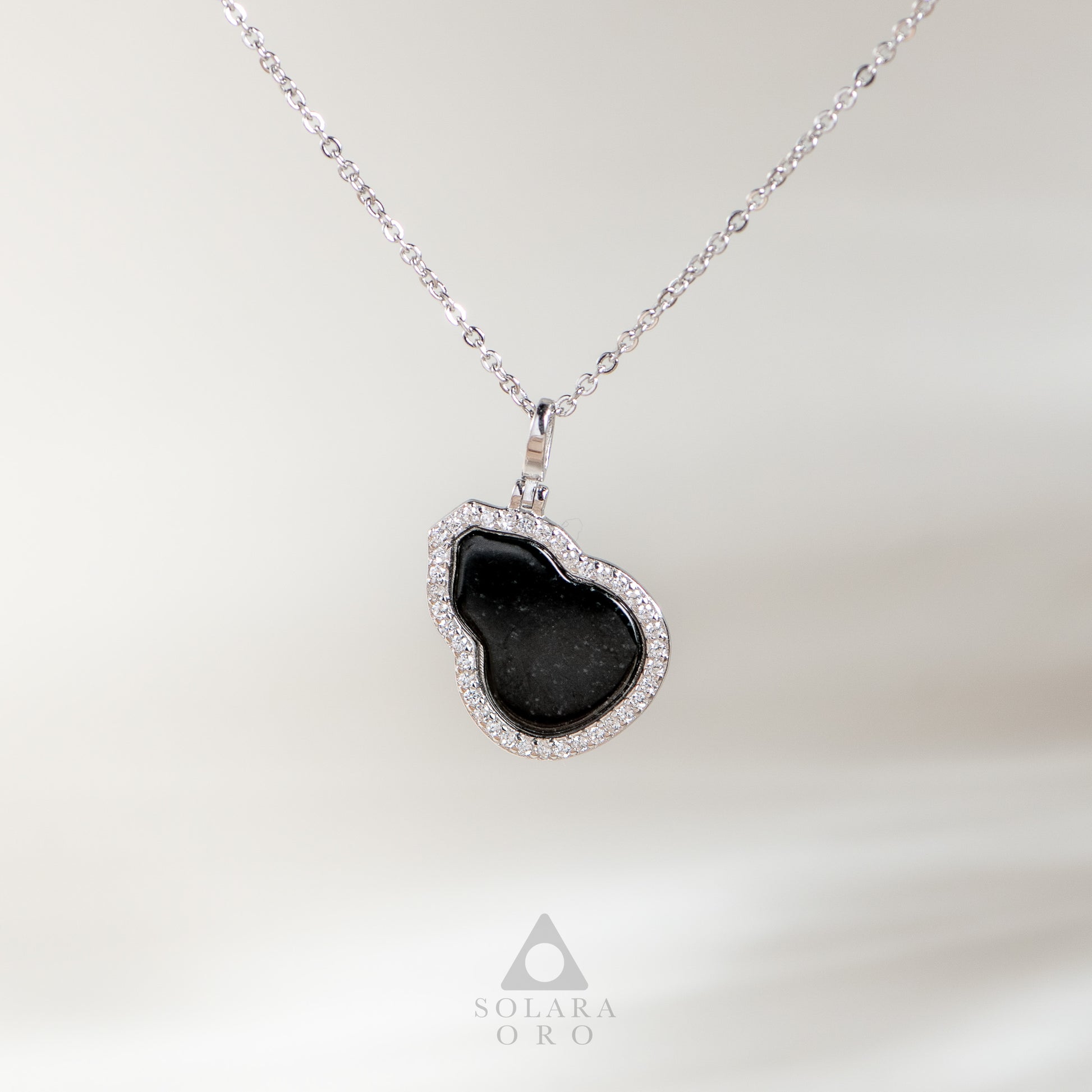 Heart-shaped black pendant necklace on a white background with Solara Oro logo.