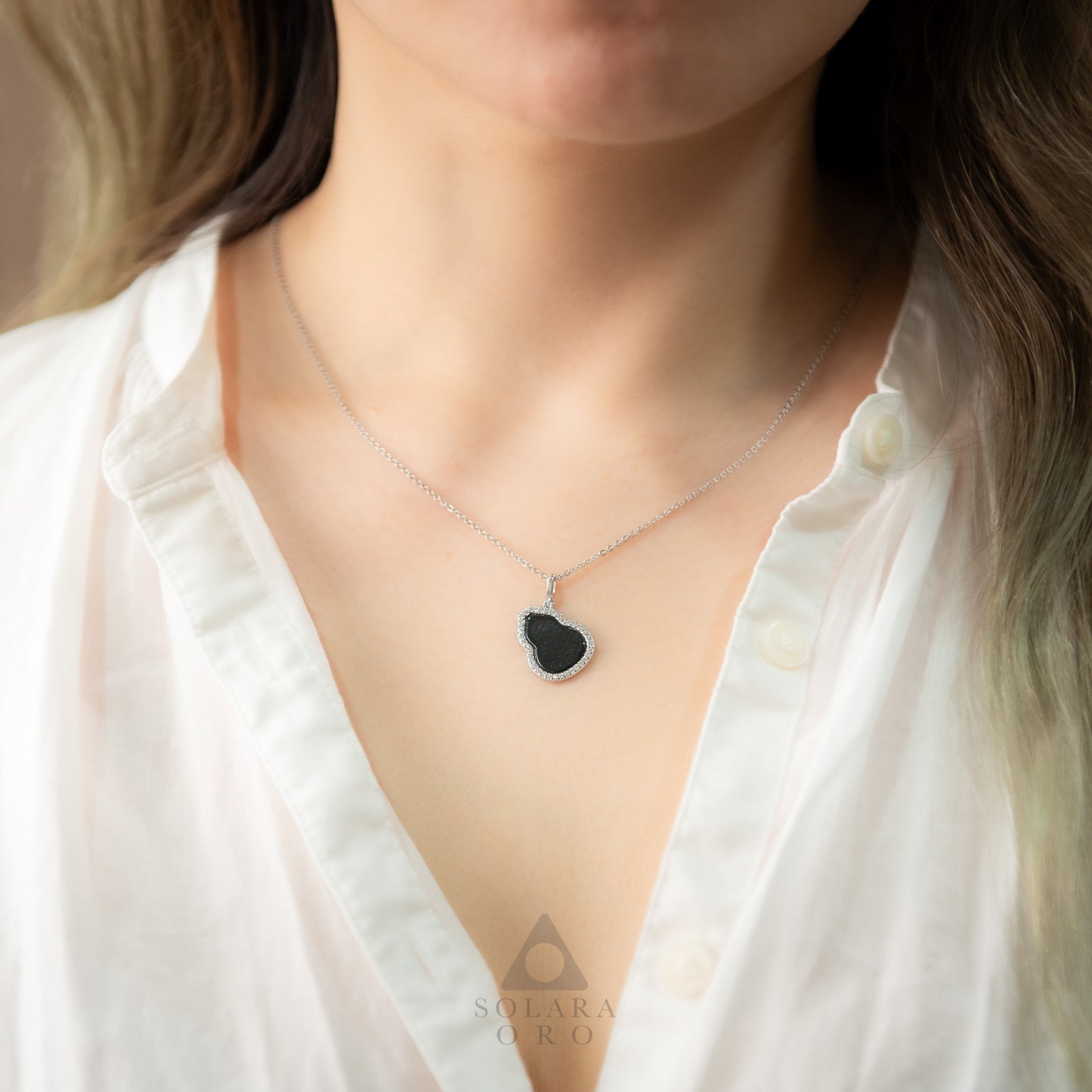 Necklace with a heart-shaped pendant worn by a person in a white shirt, with 'Sulara' brand visible.