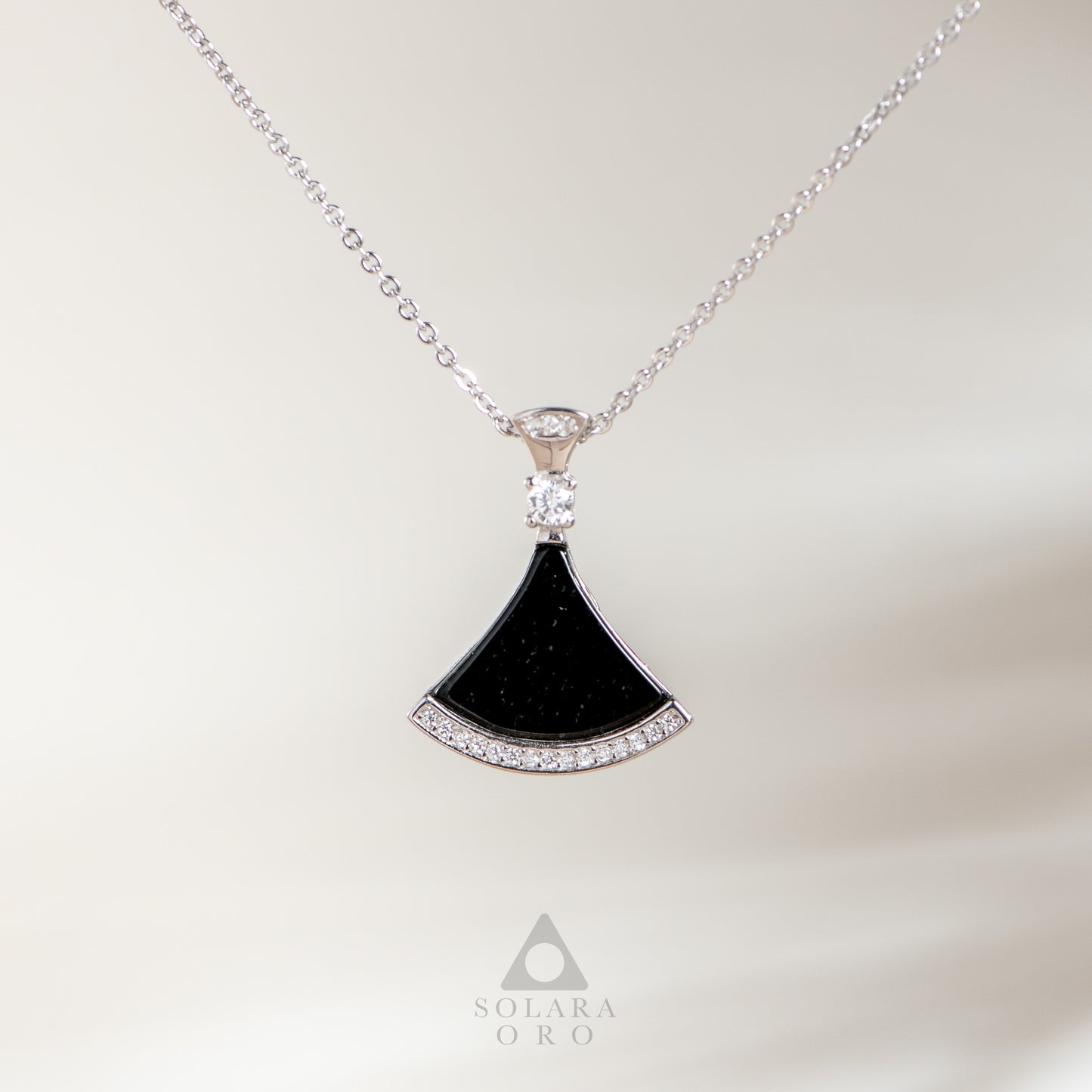 Black fan-shaped pendant with diamonds on a silver chain against a white background, featuring the Solara Oro logo.