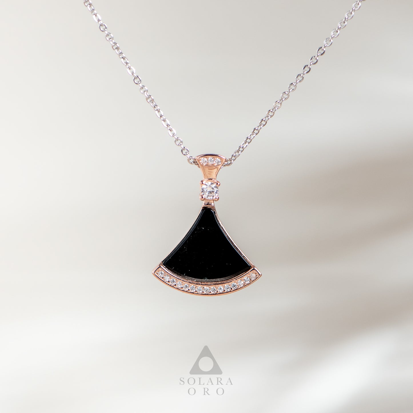 Necklace with a black pendant and rose gold accents on a light background